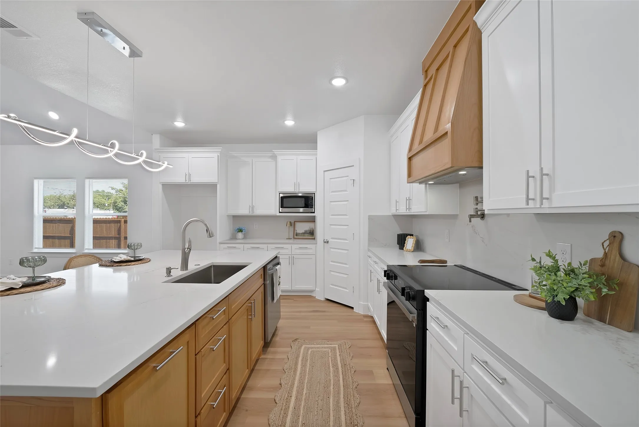Kitchen featuring a central island with an undermount sink, white countertops, and wood-finish cabinetry