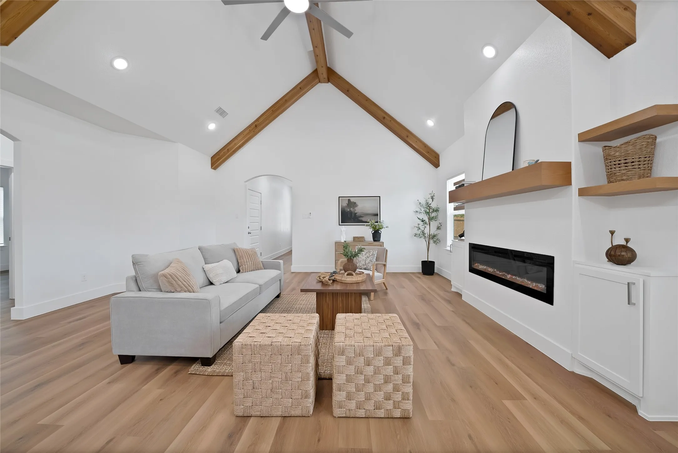 Vaulted ceiling with exposed wood beams, wood-finish flooring, built-in electric fireplace, and recessed lighting