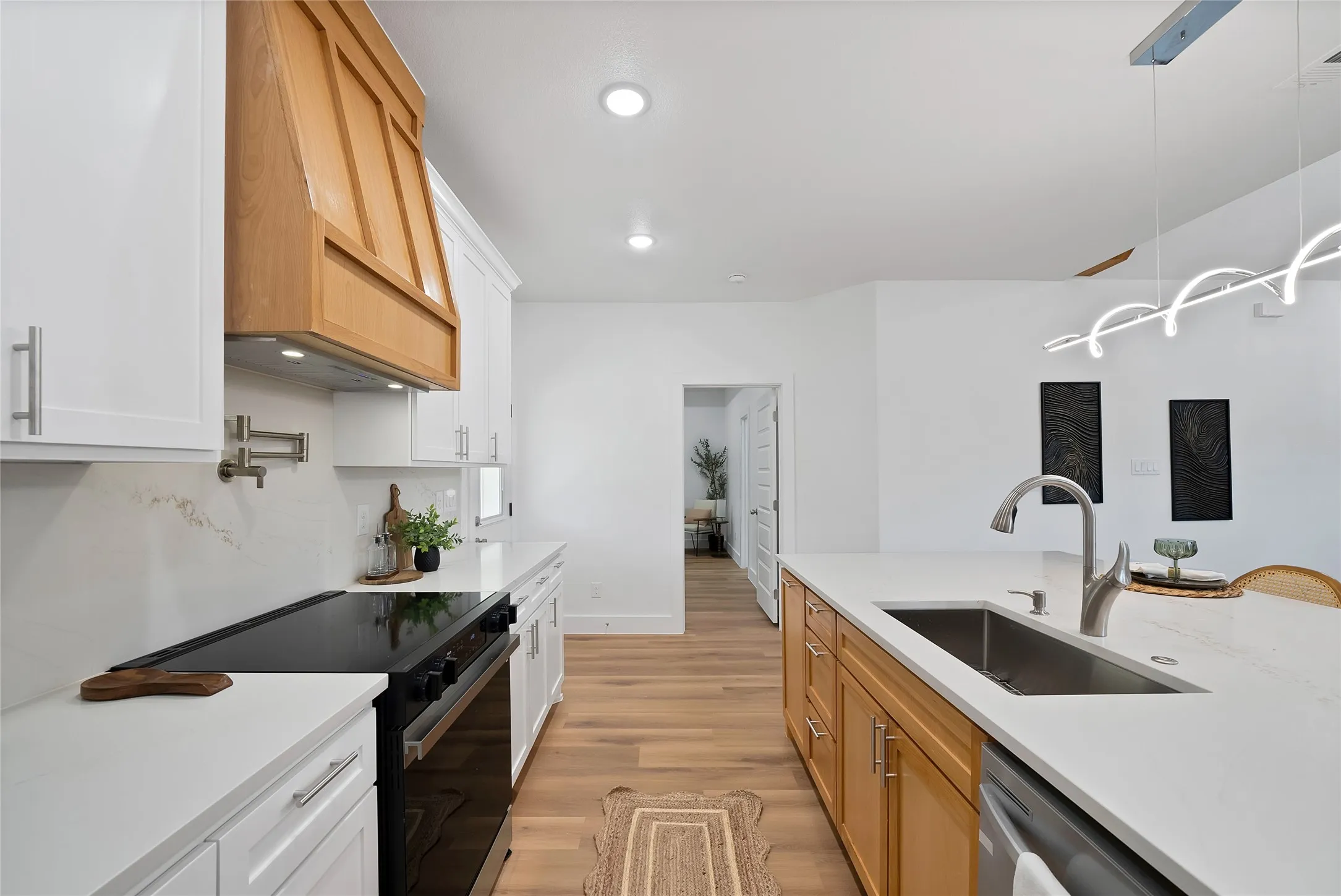 Modern kitchen featuring white cabinetry, light wood-finish flooring, a stainless steel sink, and recessed lighting