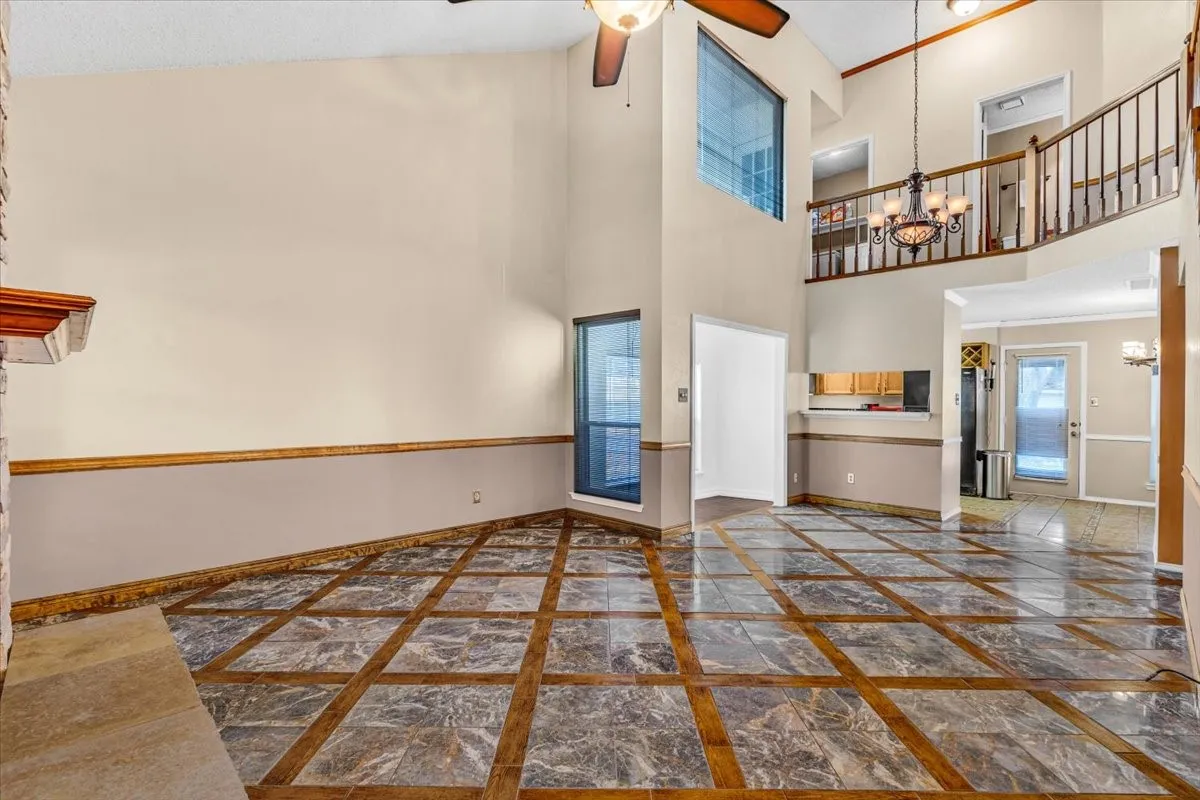 Soaring ceilings with transom windows, stone-clad fireplace, and an elegant chandelier.