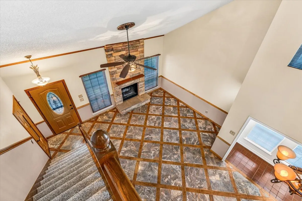 View of Living Room from above. With Soaring ceilings with transom windows, stone-clad fireplace, and an elegant chandelier.