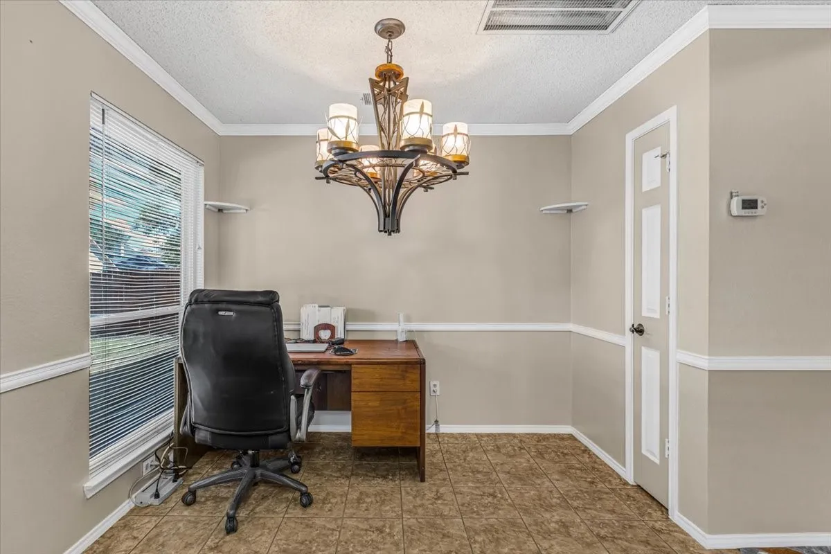 Textured tile flooring, decorative chandelier, crown molding, chair rail molding, and a paneled door