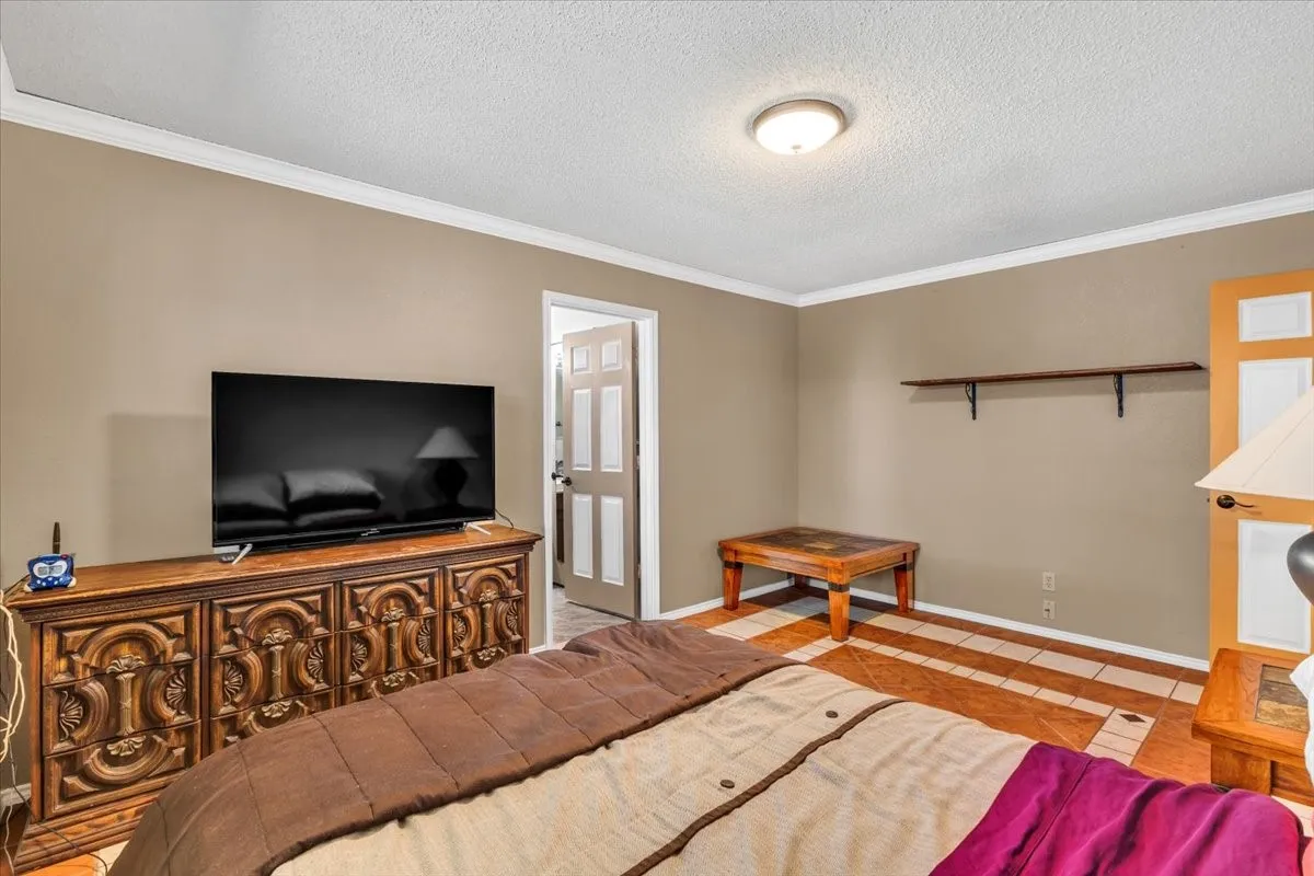 Crown molding, neutral wall color, built-in shelving, tile flooring with decorative accents, and a paneled door