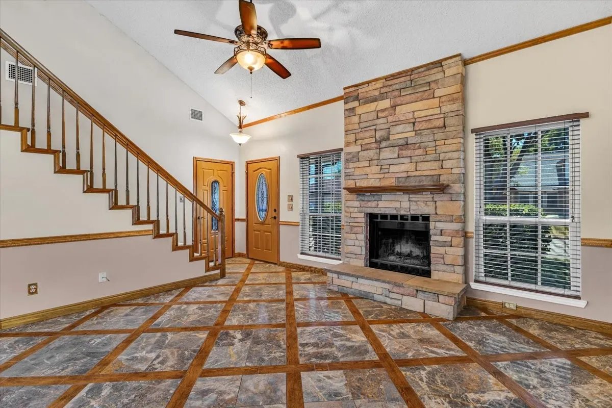 This living room view features soaring ceilings with transom windows, a stone-clad fireplace, and an elegant chandelier.
