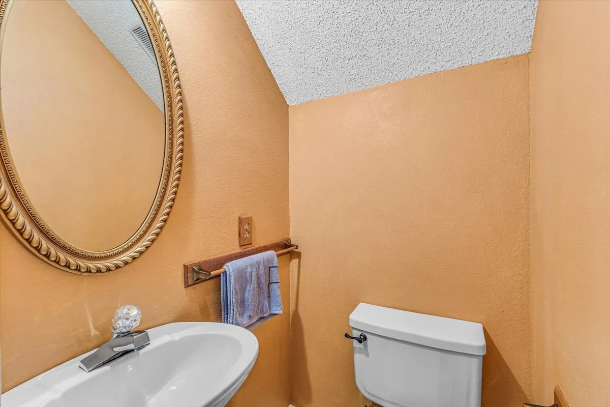 Half Bath with Pedestal sink with a crystal-accented faucet and an ornate oval mirror.