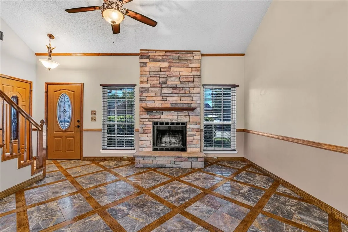 Soaring ceilings with transom windows, stone-clad fireplace, and an elegant chandelier.