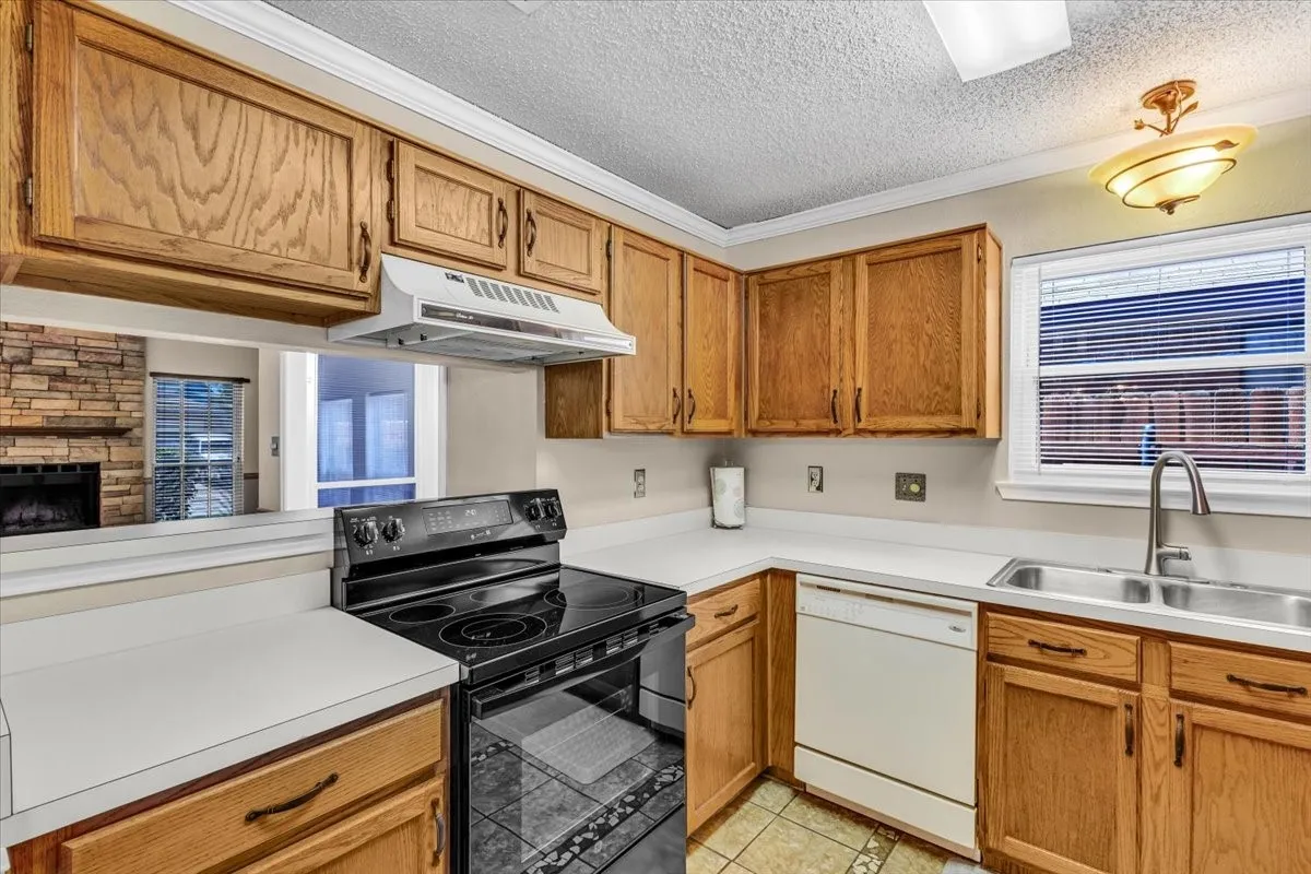 Kitchen featuring wood cabinetry, white countertops, a stainless steel double basin sink with a gooseneck faucet, a new built-in electric range, and a dishwasher