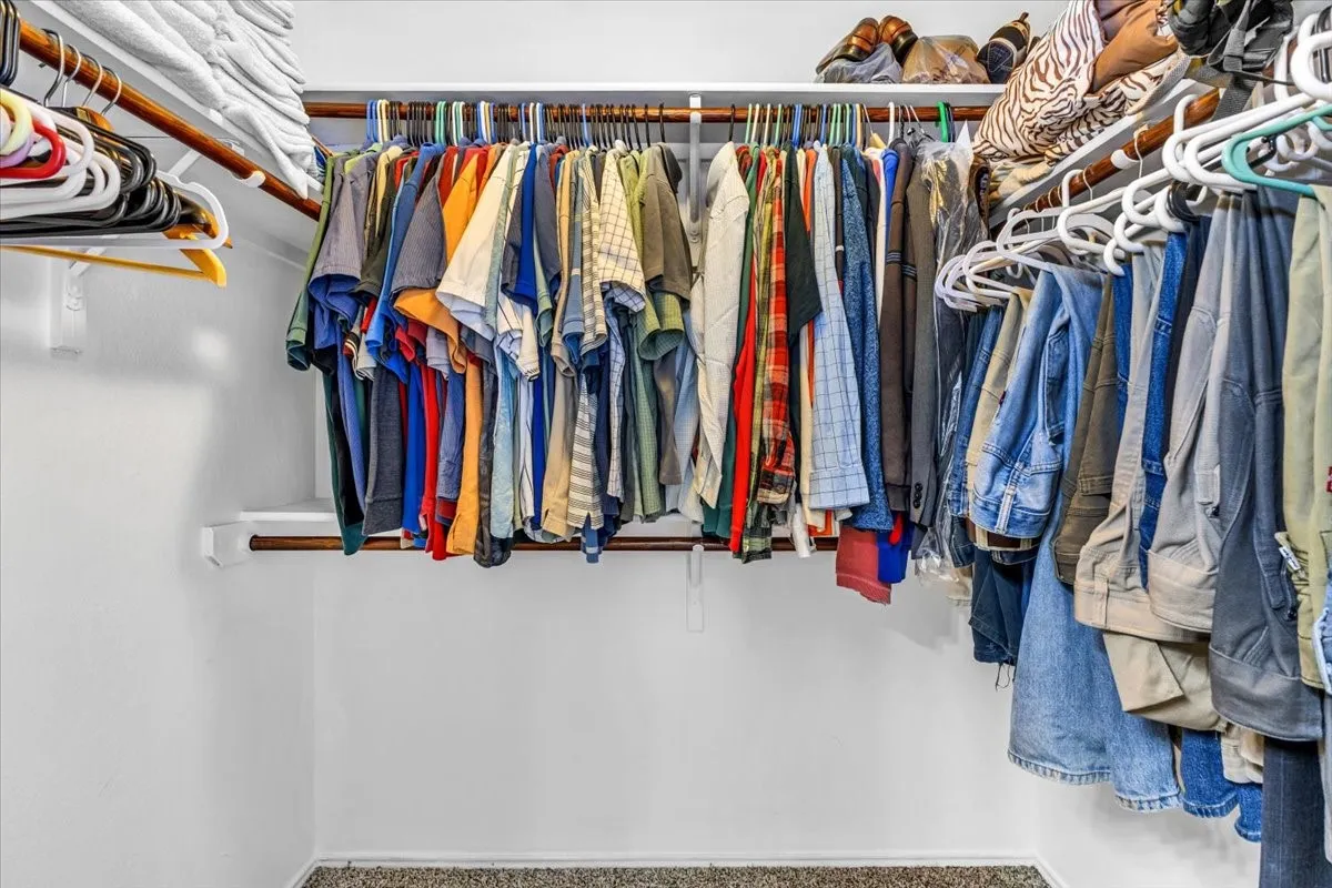Primary Bedroom Walk-in Closet with Built-in closet system featuring multiple hanging rods and integrated shelving for organized storage