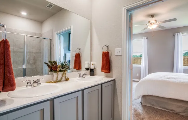 Bathroom featuring a dual vanity with light-toned countertops and gray cabinetry