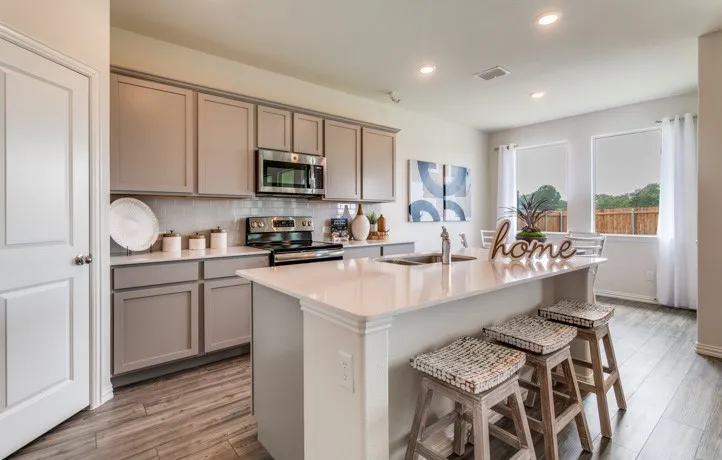 Kitchen featuring light gray cabinetry, stainless steel appliances, white subway tile backsplash, a large island with a sink, and wood-finish flooring