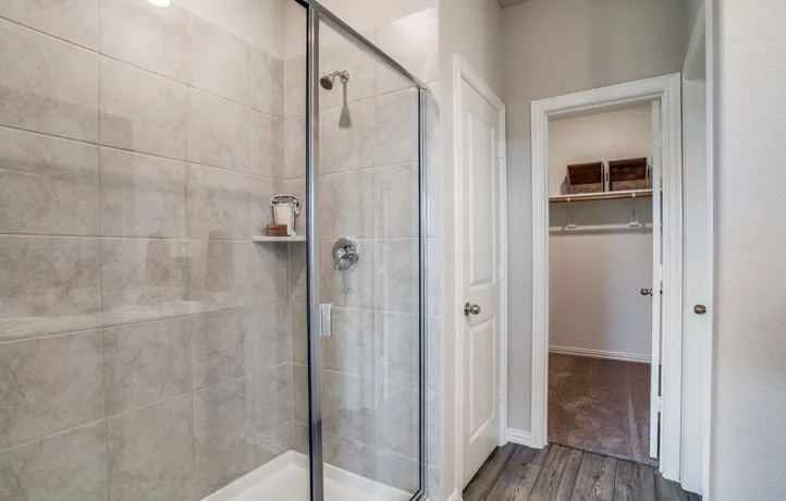 Shower enclosure featuring clear glass panels, a chrome shower head, and an integrated shelf