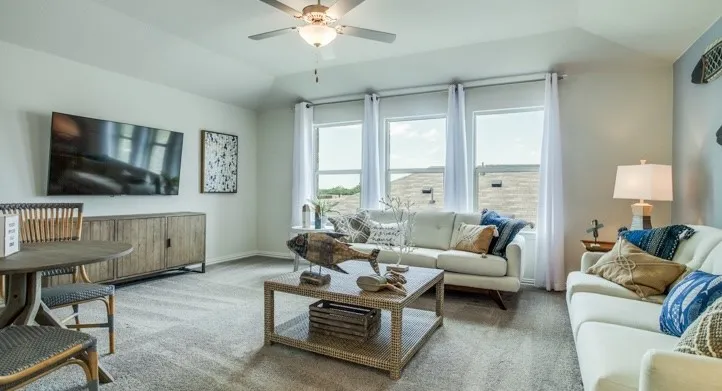Living area featuring carpet flooring, a ceiling fan with integrated lighting, and three large windows