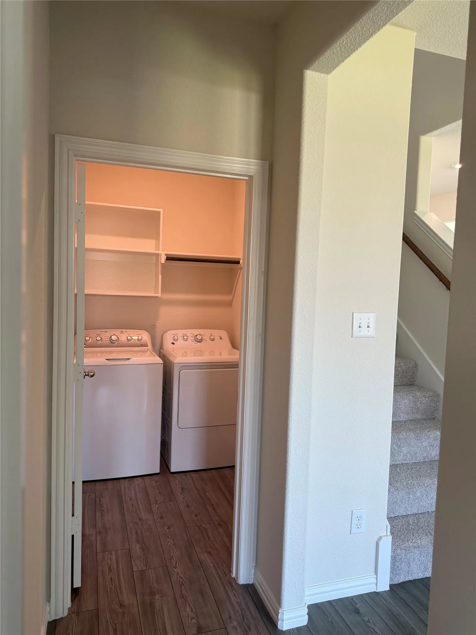 Dedicated laundry alcove with wood-finish flooring and integrated shelving