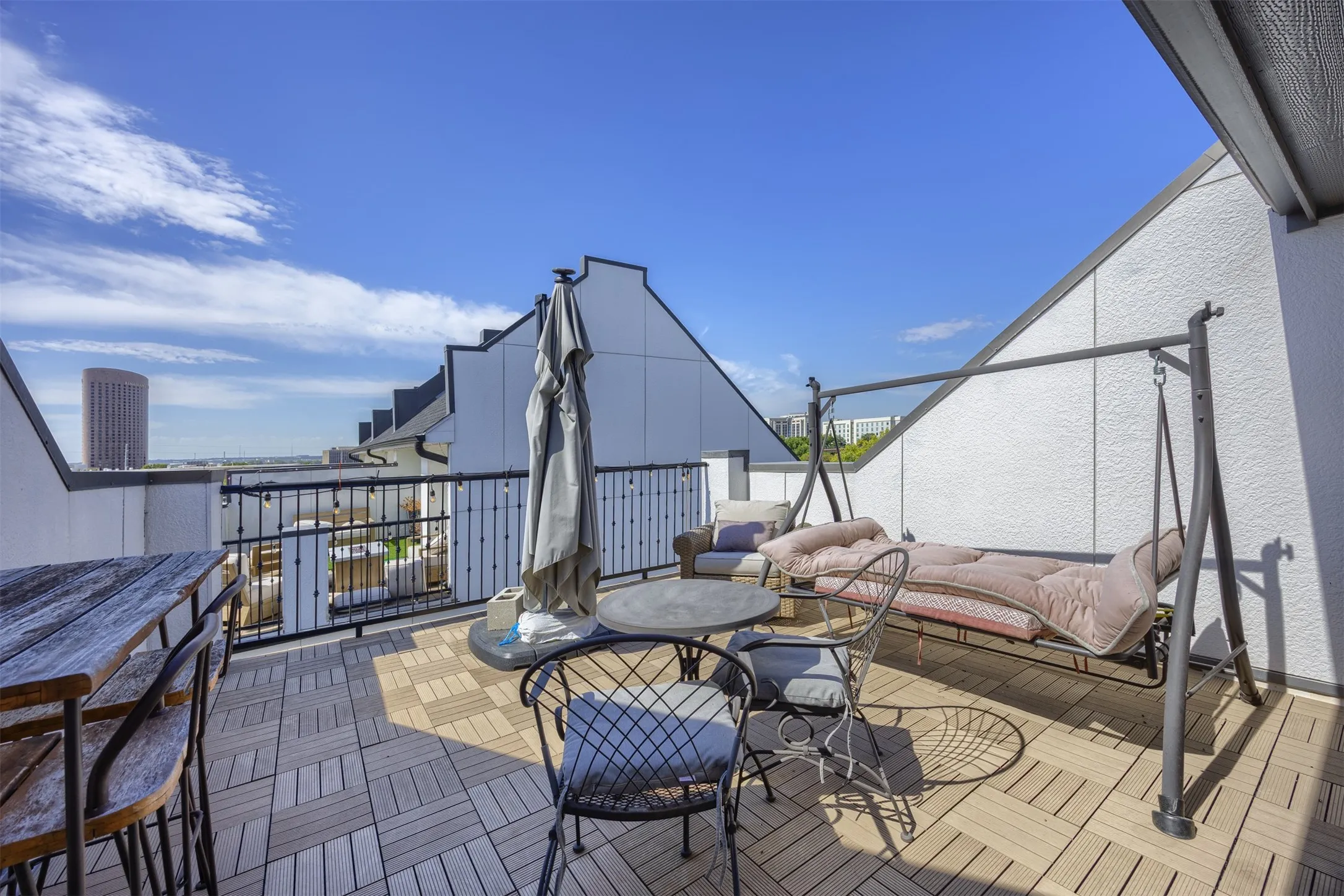 Rooftop deck featuring plank-style tile flooring, black metal railing, and a white stucco exterior