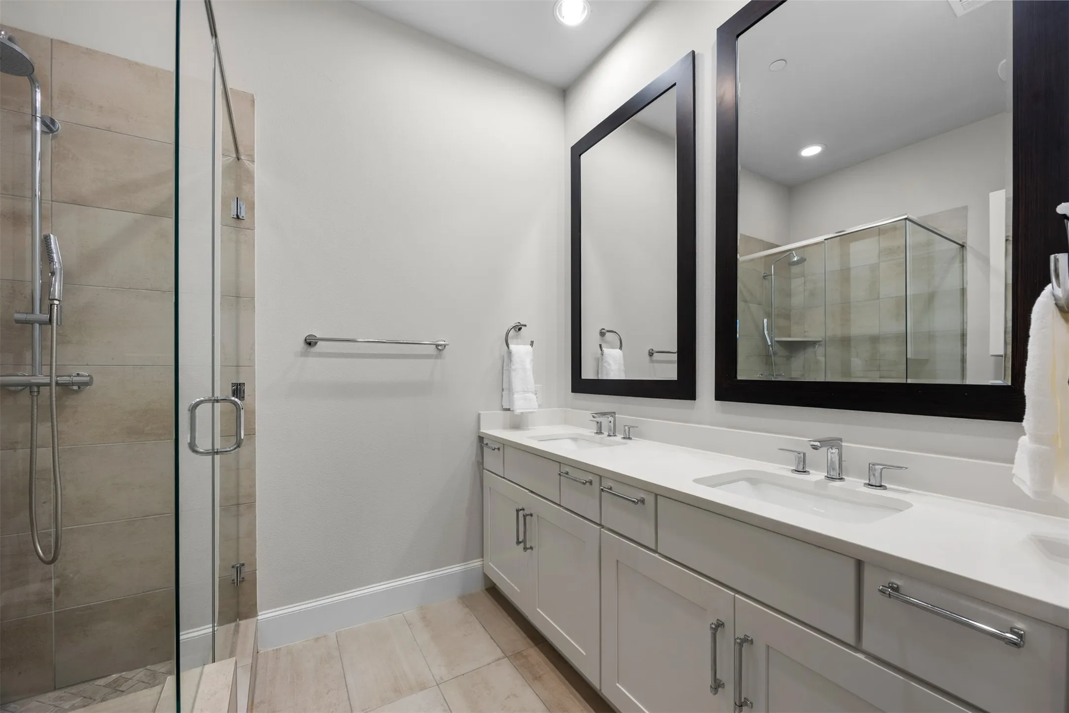 Dual vanity with undermount sinks, white countertops, and framed mirrors