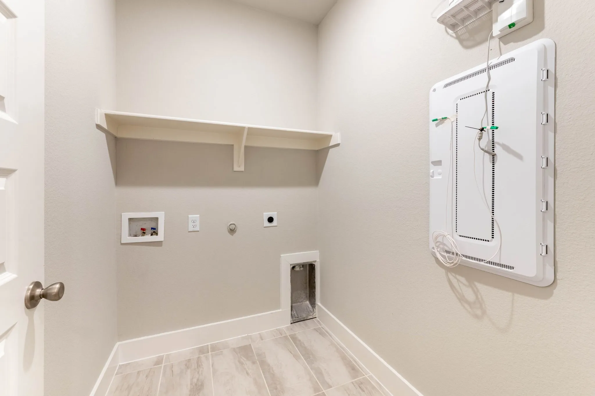 Utility space with tile flooring, a built-in shelf, and appliance connections