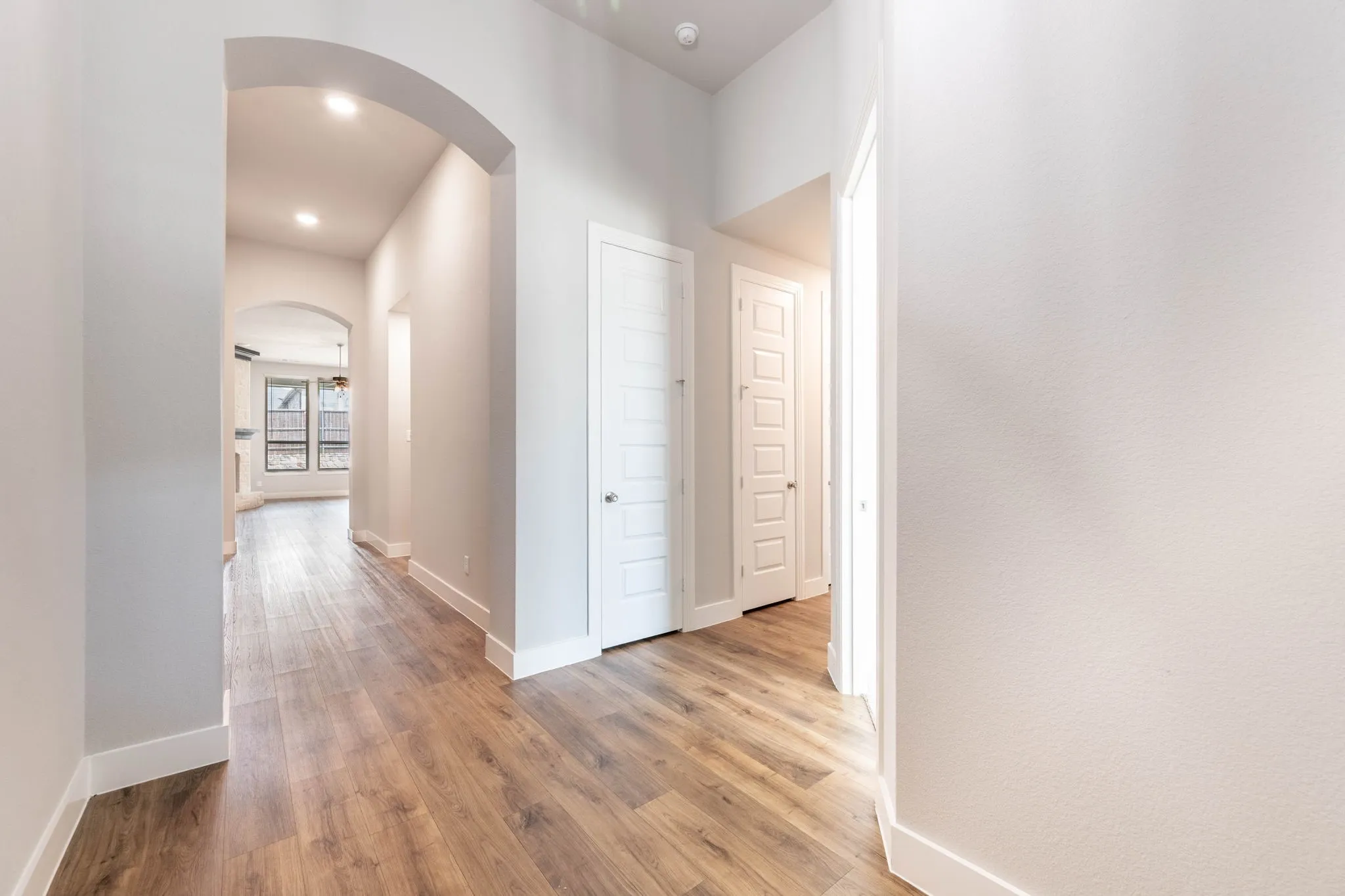 Hallway with wood-finish flooring, recessed lighting, and arched doorways