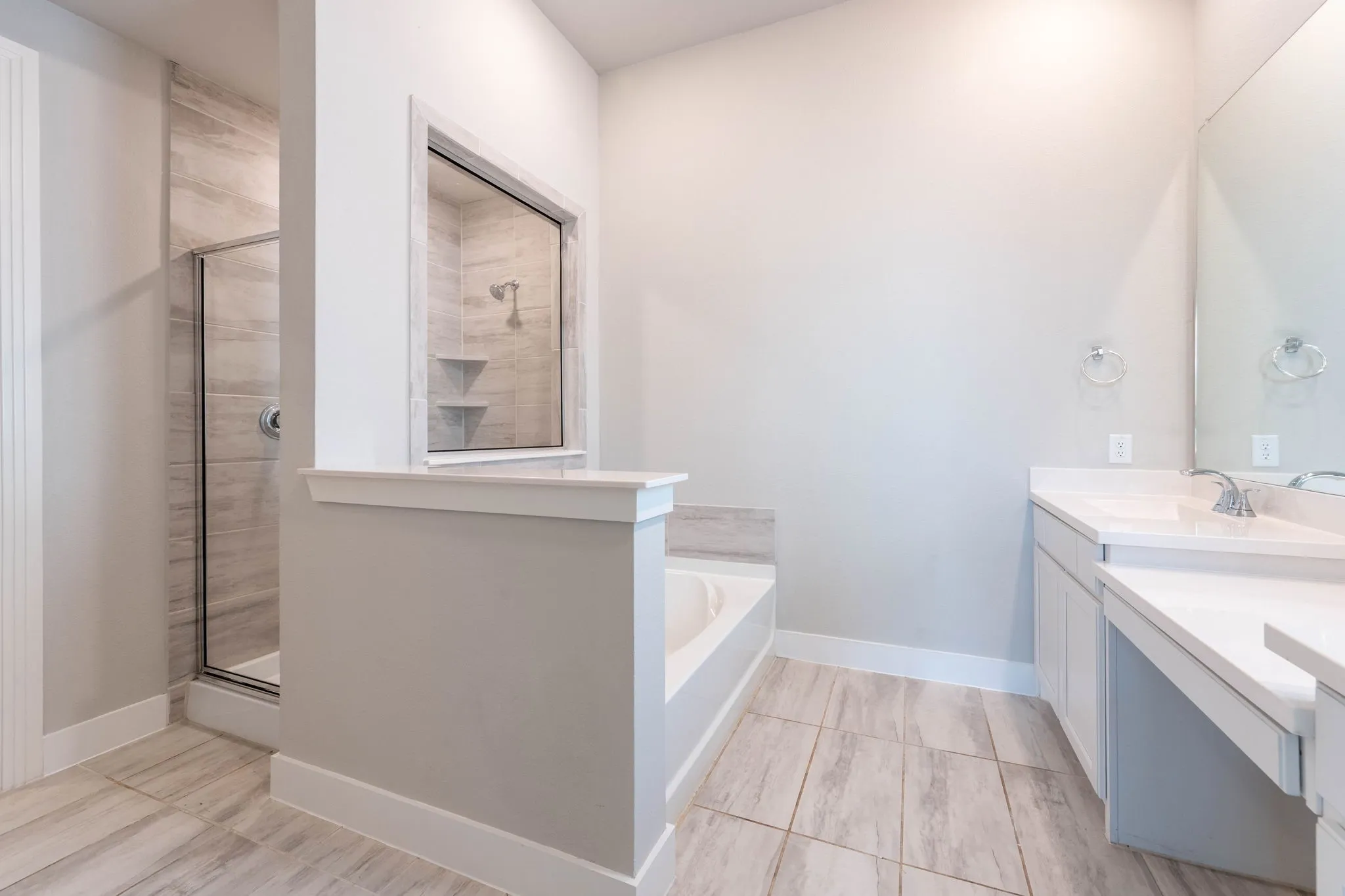 Walk-in shower with glass enclosure and tiled walls, separate soaking tub, and dual vanity with integrated sinks