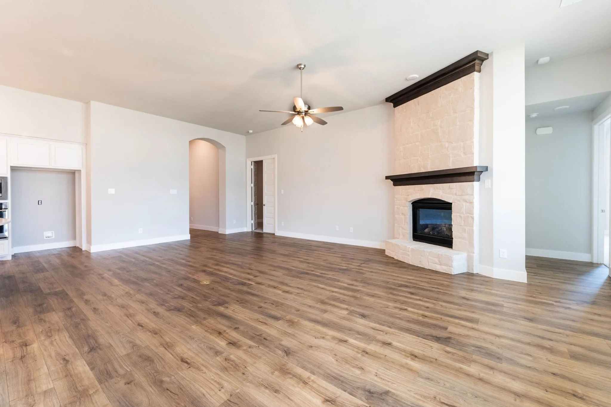 Wood-finish flooring throughout, featuring a stone-clad fireplace with a dark wood mantel