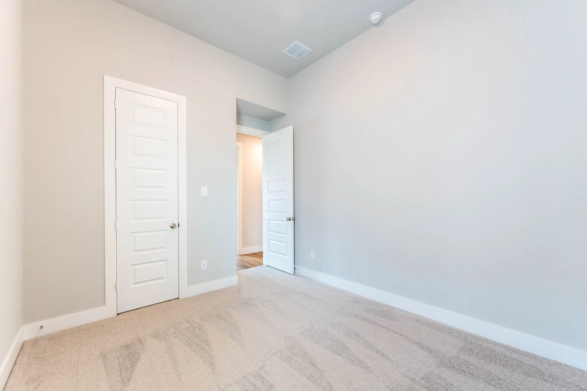 Neutral wall paint, light-toned carpet flooring, white trim, and a white paneled door