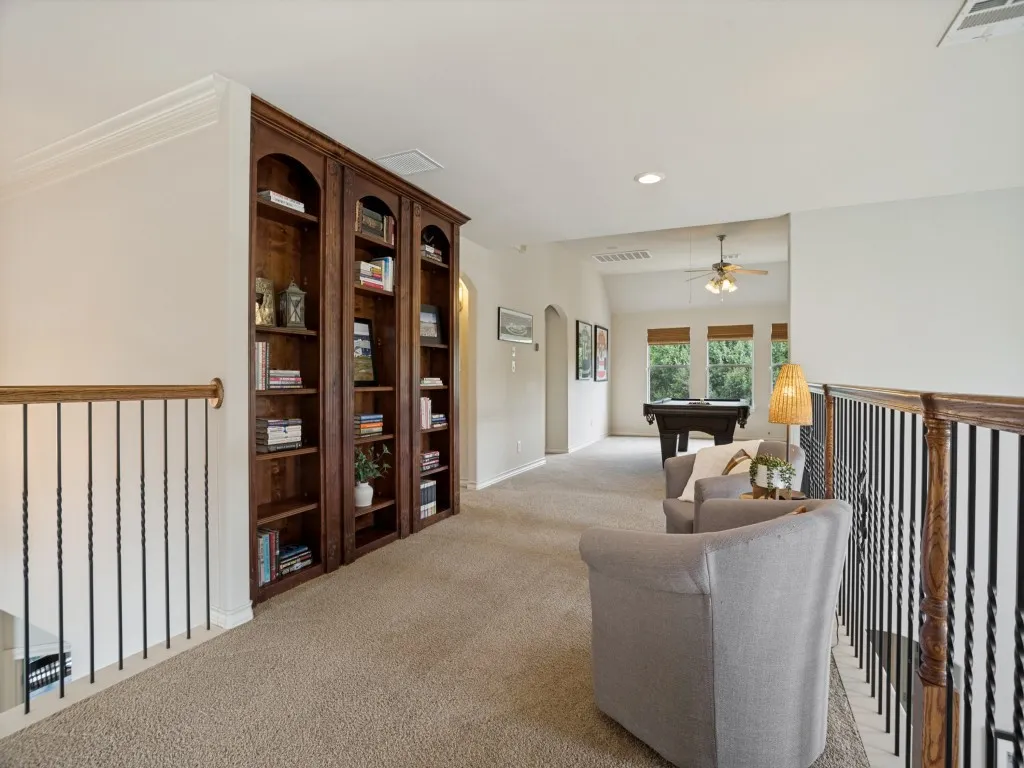 Open upstairs living space with built-in bookcases and seamless connection to the game room—one of multiple flexible living areas in this 4,160-square-foot Flower Mound home.