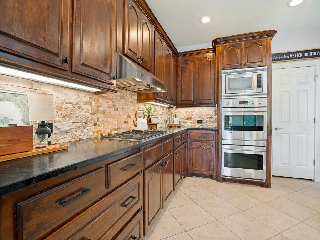 Renovated kitchen featuring rich wood cabinetry, stone backsplash and premium appliances including Bertazzoni, Viking and KitchenAid.