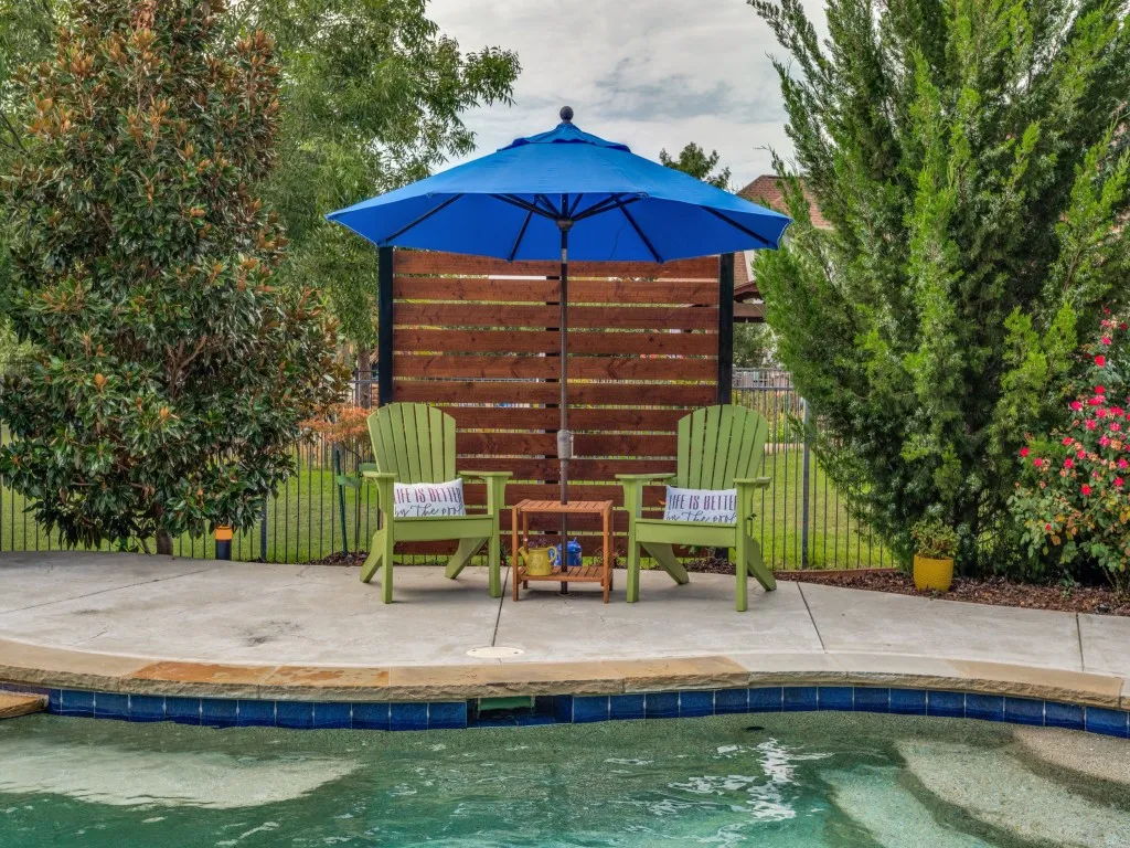 Thoughtfully landscaped poolside retreat with dedicated seating area, mature trees and peaceful surroundings designed for relaxing outdoors.