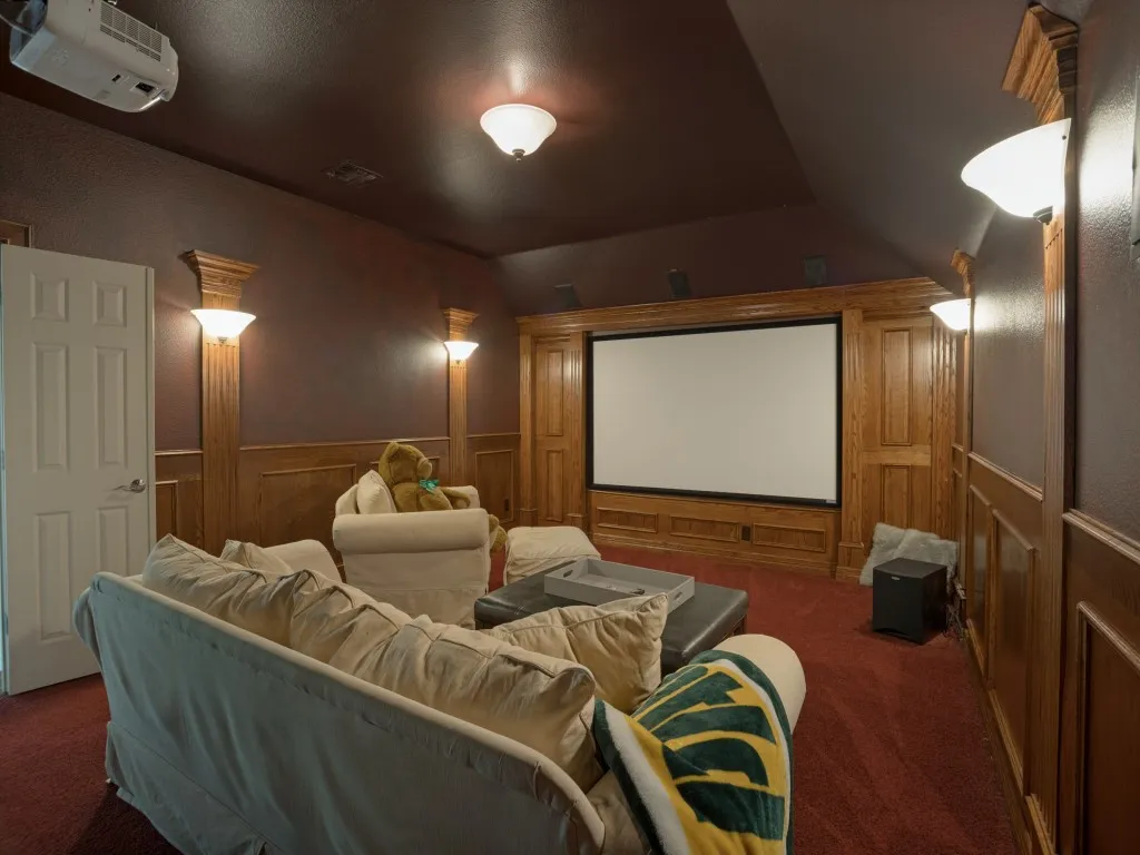 Dedicated home theatre featuring an Epson HD projector, large projection screen, built-in wood detailing and professional Sanus AV equipment.