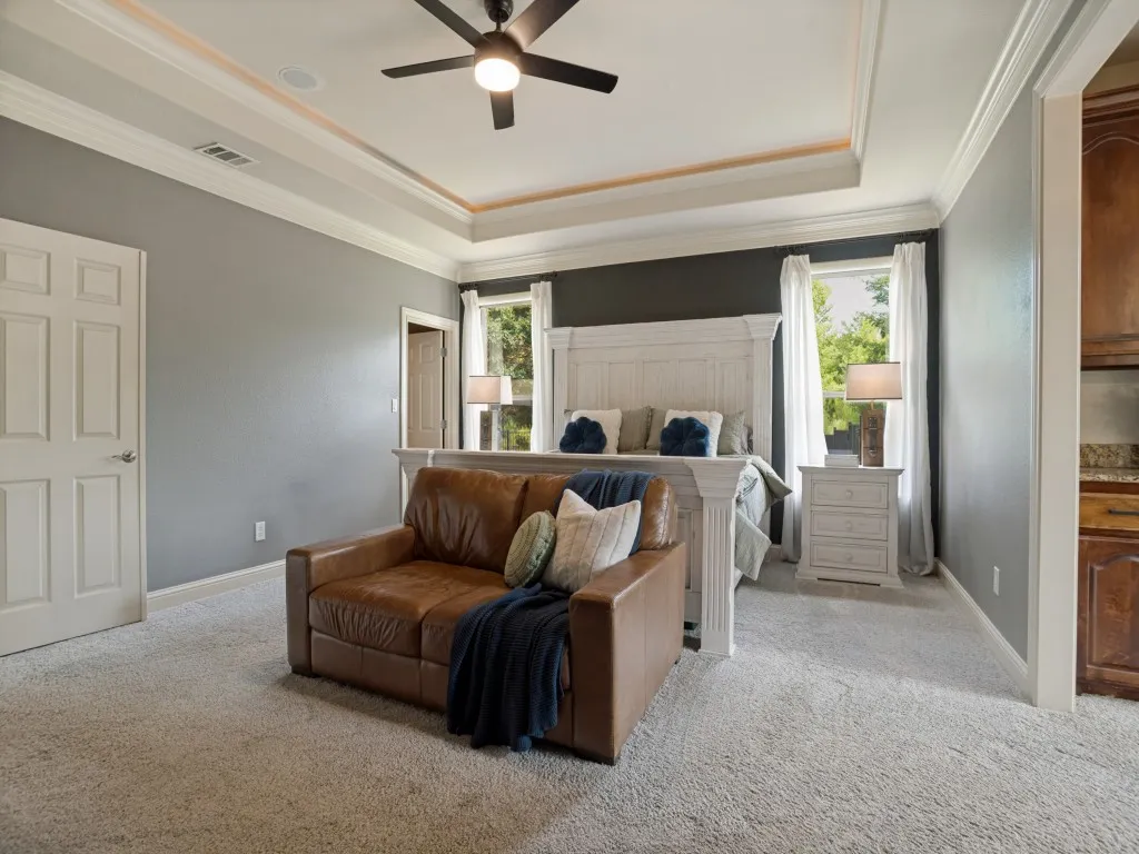Spacious primary retreat with illuminated tray ceiling, sitting area and direct access to the ensuite bath and custom walk-in closet.