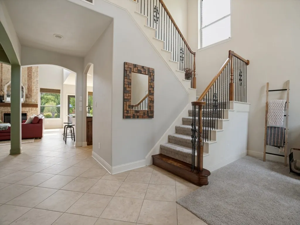 Grand two-story entry with soaring ceilings, detailed staircase and an open view into the main living spaces of this Flower Mound home.