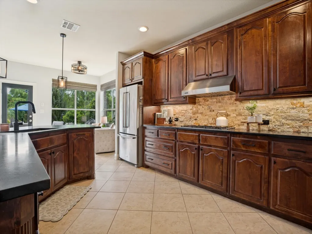 Beautifully updated kitchen with honed black granite countertops, extensive cabinetry, stone backsplash and abundant prep and storage space.