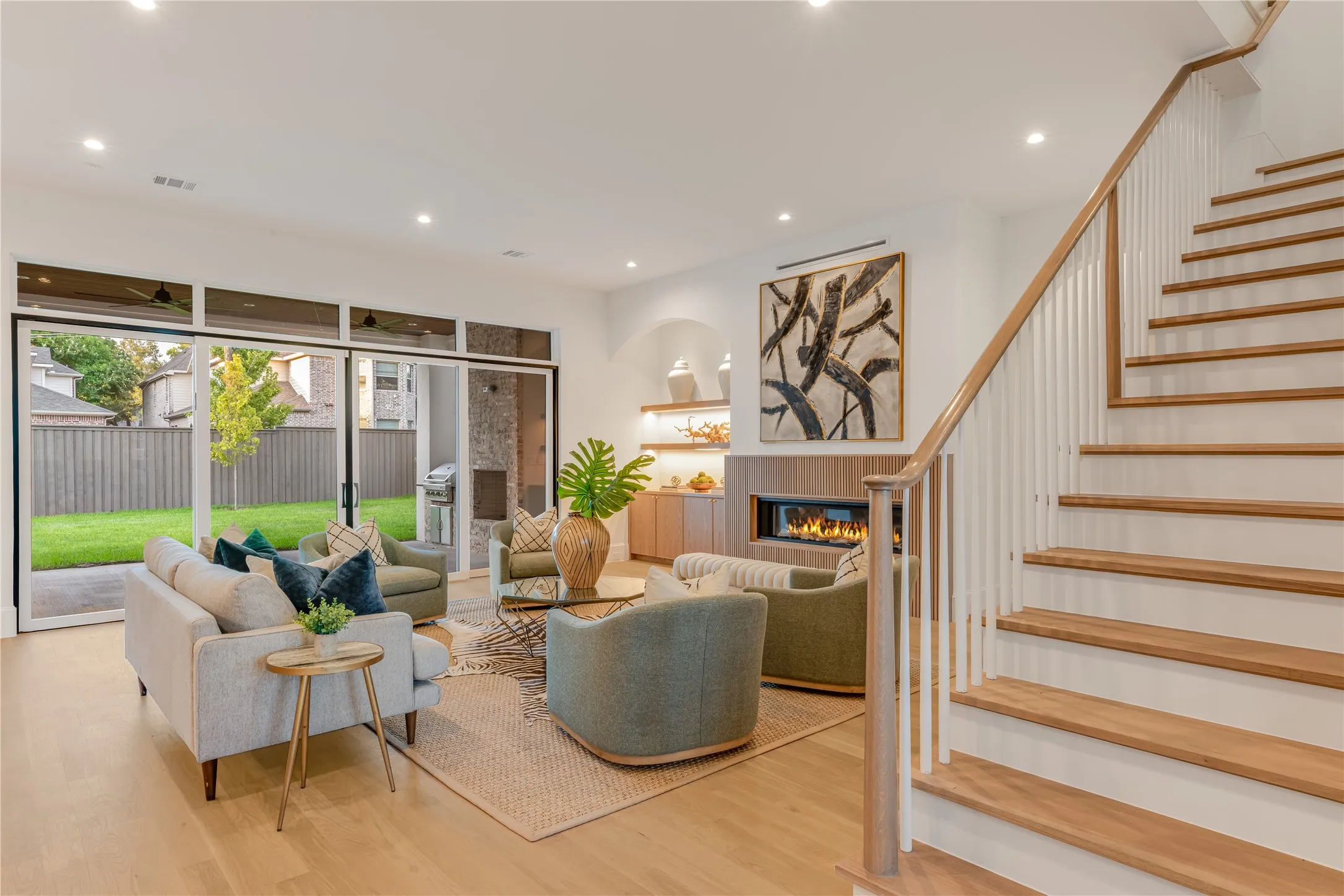 Wood-finish flooring, recessed lighting, built-in fireplace, sliding glass doors, and a wood-finish staircase with white risers