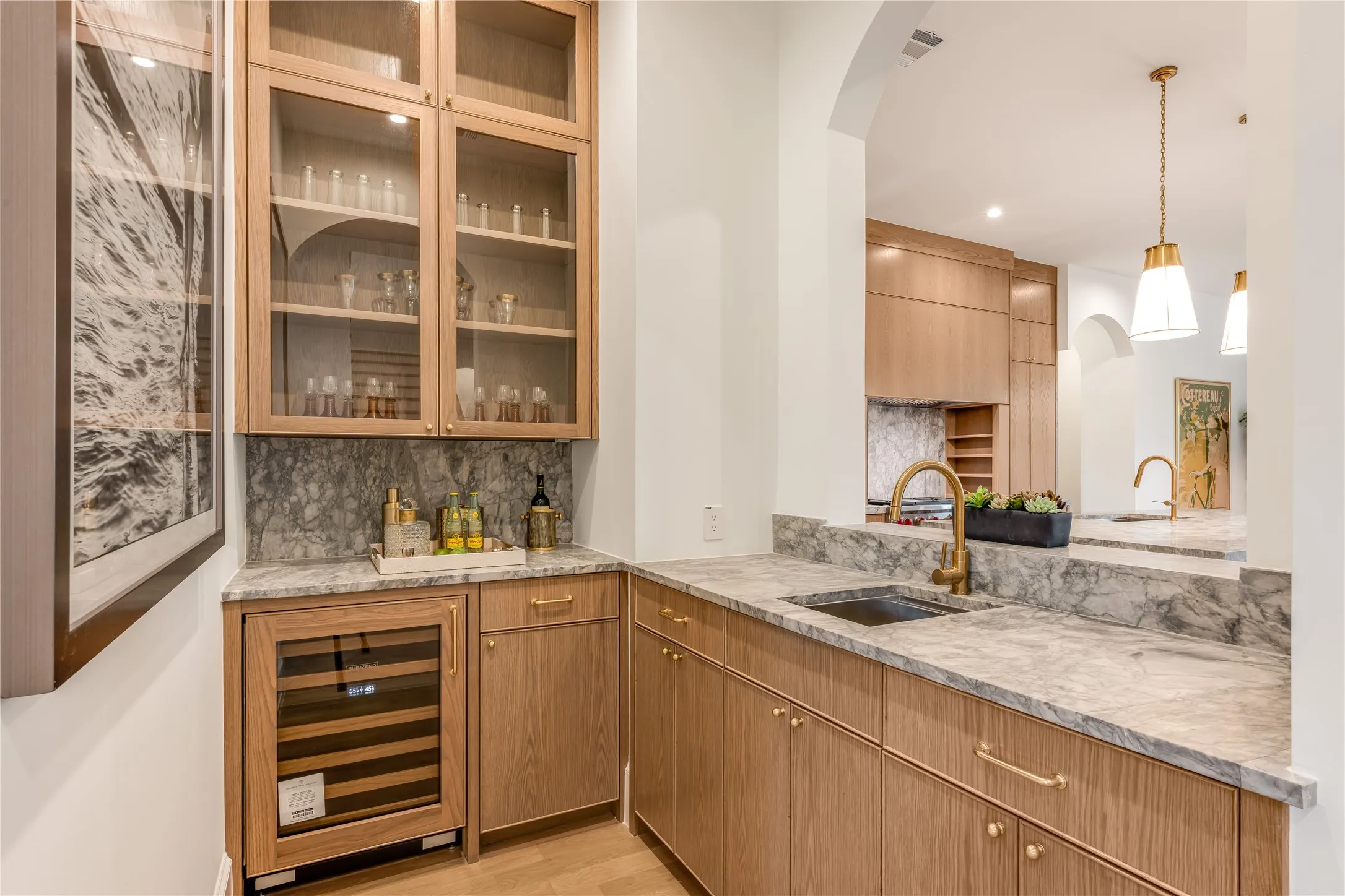 Built-in wet bar with wood-finish cabinetry, glass-front upper cabinets, and a wine refrigerator