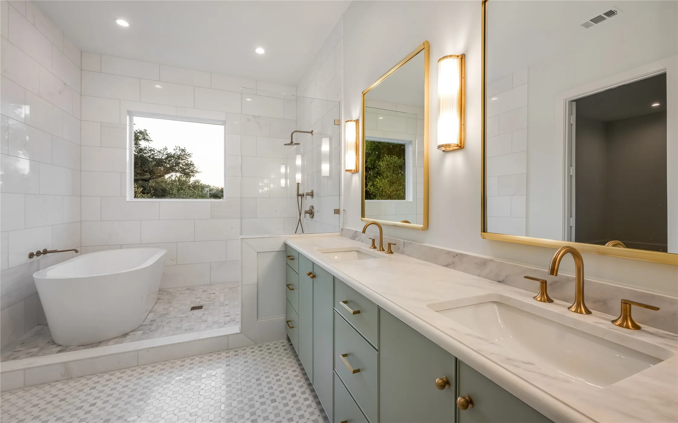 Freestanding soaking tub, walk-in shower with rain head and handheld fixtures, dual vanity with undermount sinks, gold-finish hardware, and marble-finish countertops