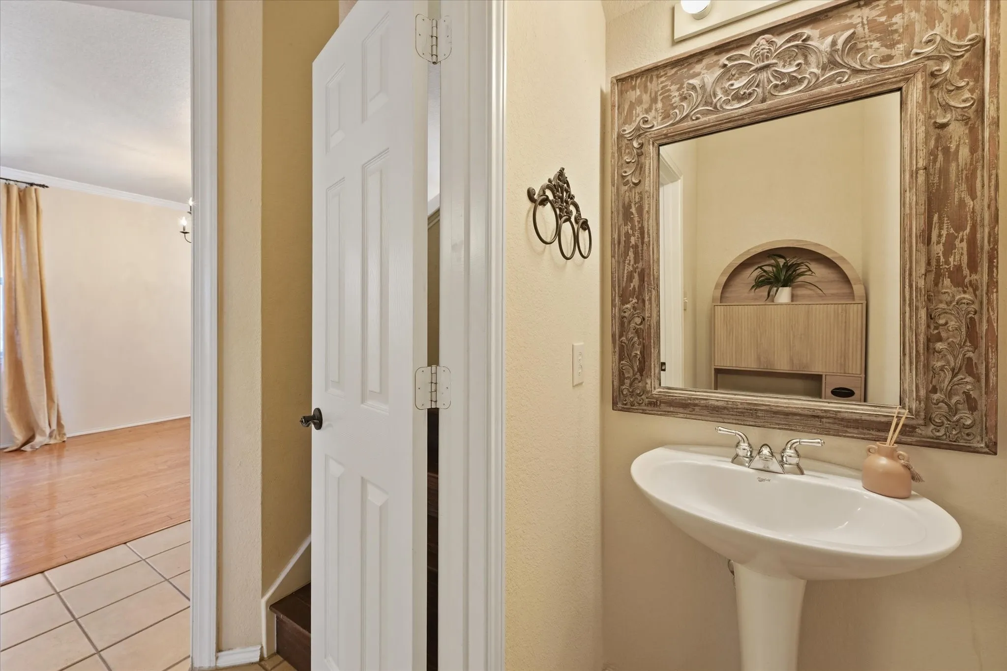 Convienient first floor half bath features a pedestal sink with an ornate framed mirror.