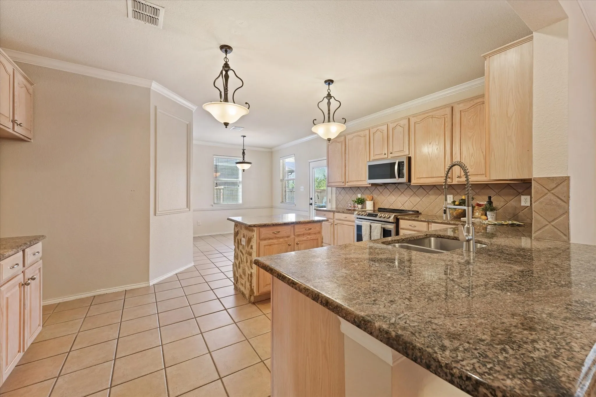 Stone and granite finishes and updated appliances create a custom build appearance to elevate this kitchen design. Just off of the family room, this open concept design is great for entertaining.