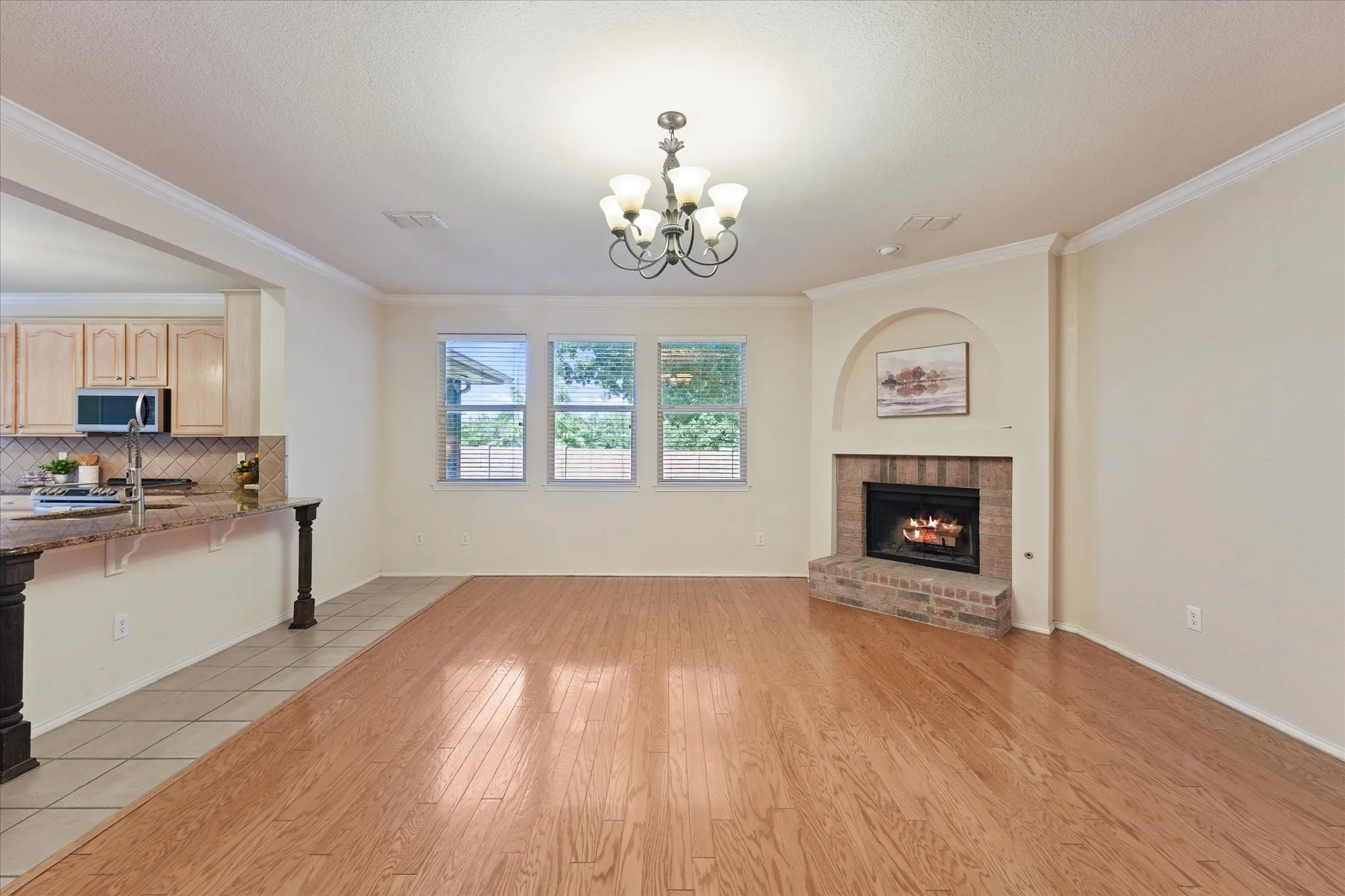 Corner brick fireplace, three large windows, wood-finish flooring with crown molding add warmth and character in this well appointed family room just off of the kitchen.