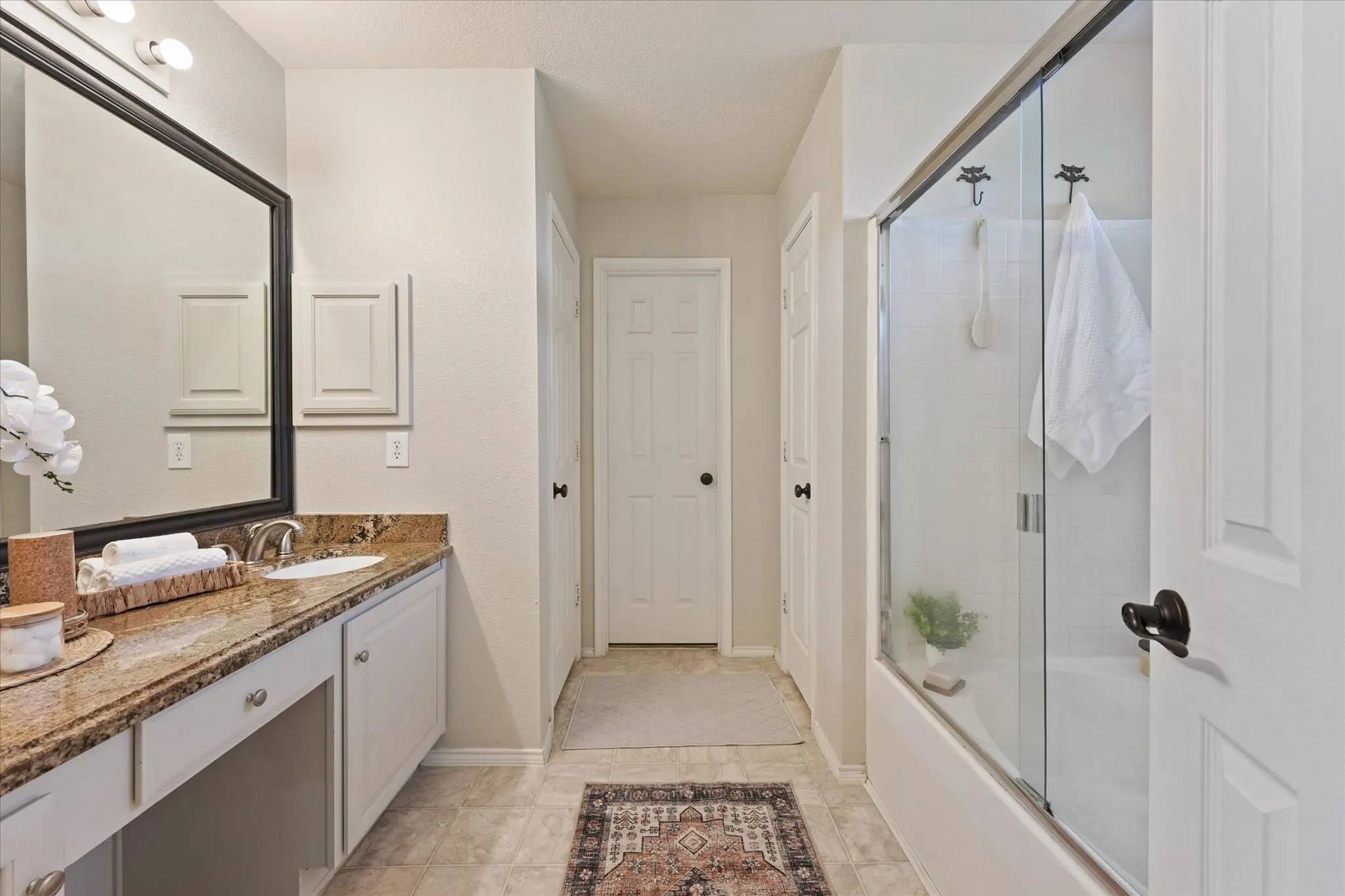 Vanity with a polished stone countertop, undermount sink, and white cabinetry