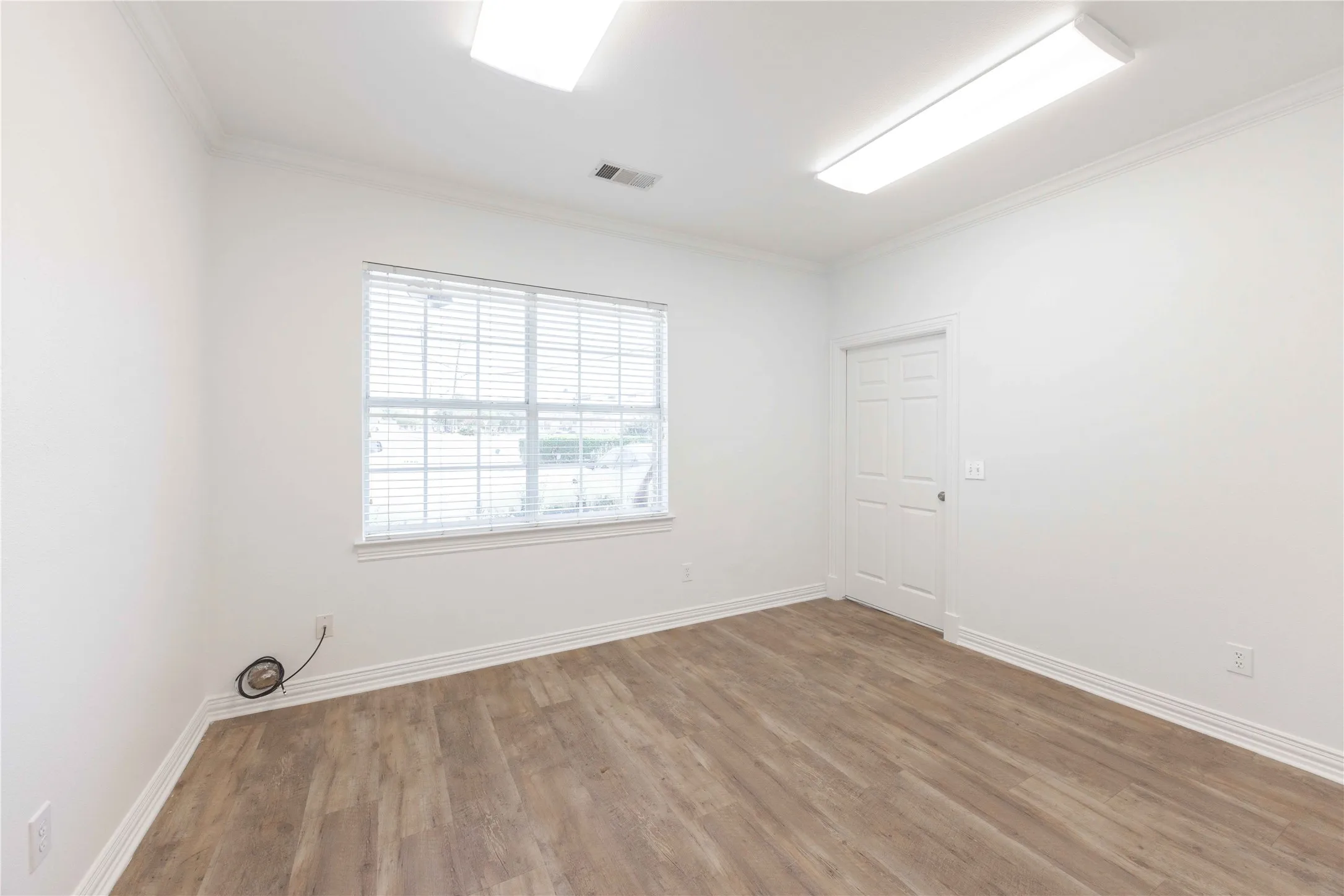 Wood-finish flooring, crown molding, white trim, recessed lighting, and a window with blinds