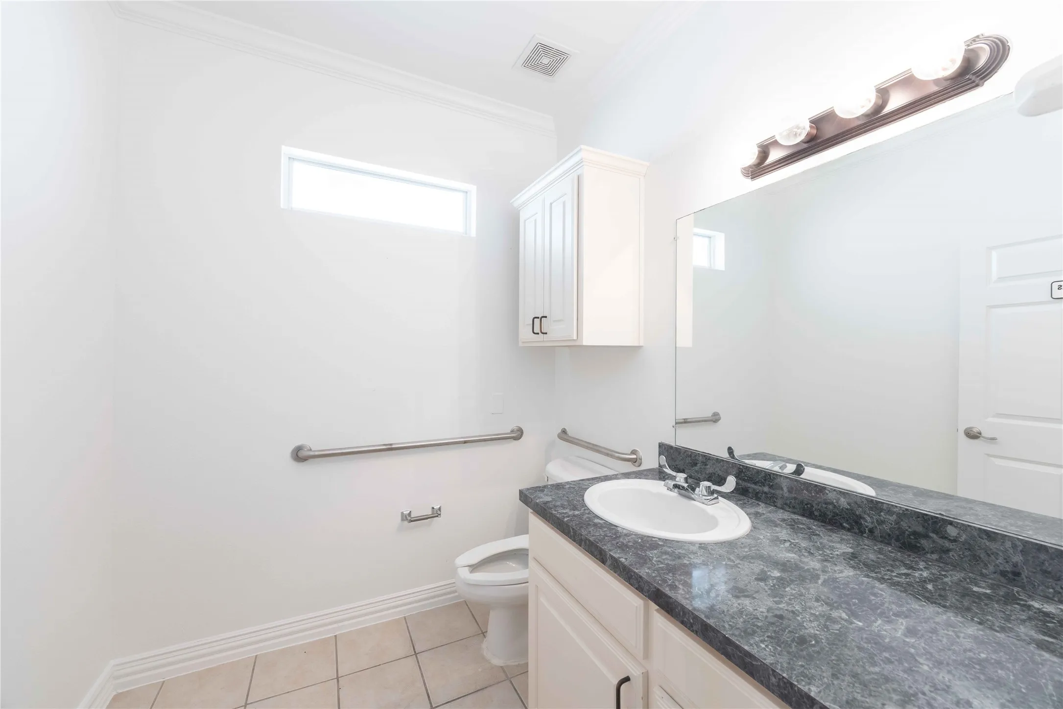 Vanity with an integrated sink, dark countertop, and large mirror