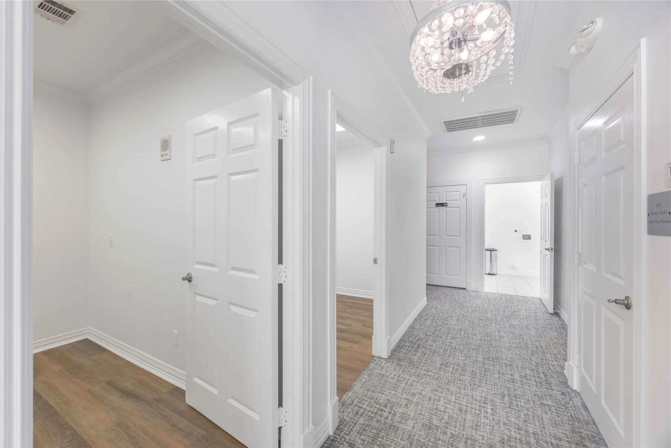 Hallway featuring a decorative chandelier, recessed lighting, crown molding, paneled doors, and carpeted flooring