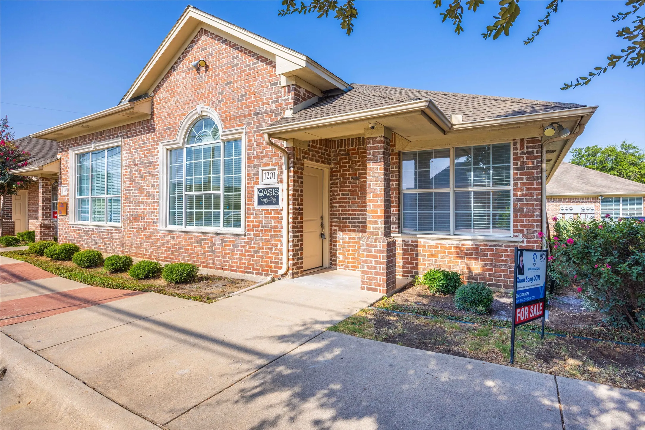 Brick exterior with arched window, multiple large windows, and established landscaping