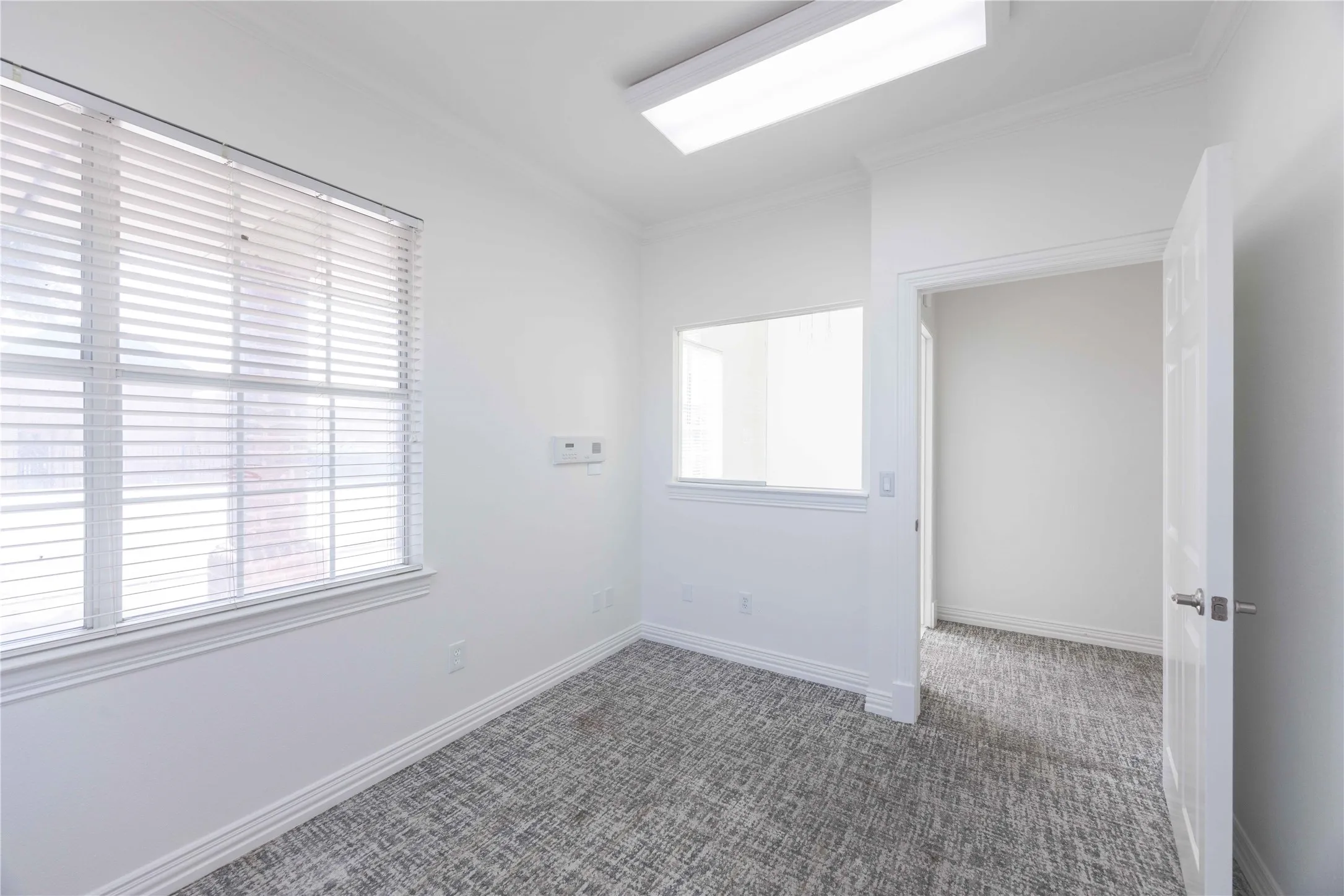 White walls, patterned carpet flooring, transom window, recessed lighting, and crown molding