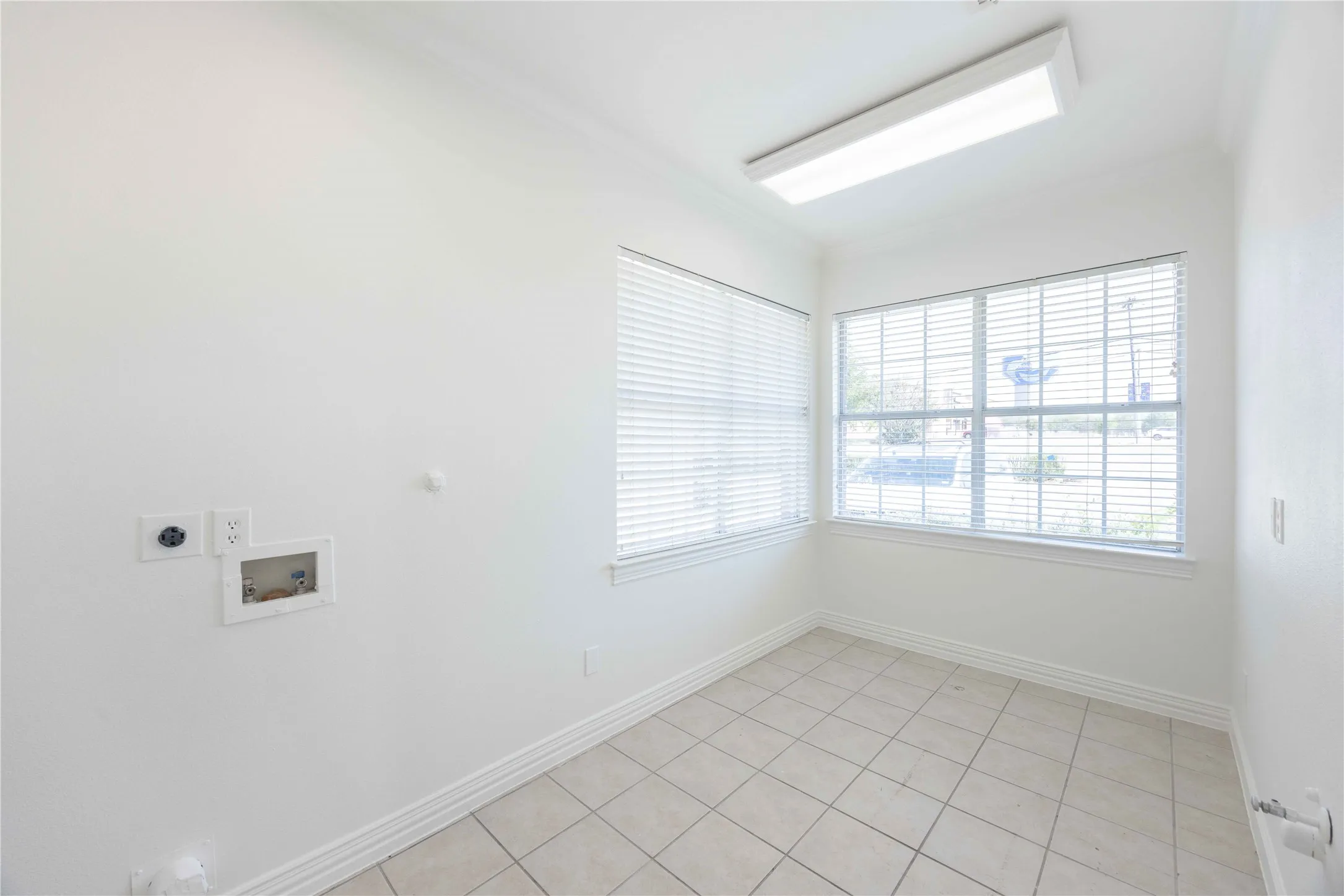 Tiled flooring, white window blinds, and overhead fluorescent lighting