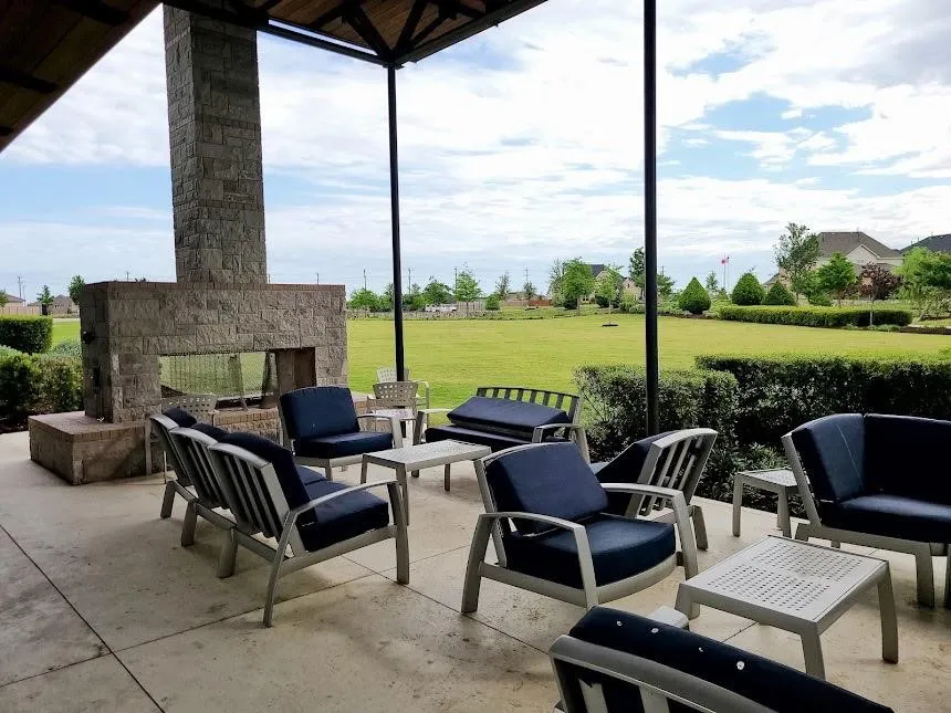 Covered outdoor patio with a stone-clad fireplace and exposed beam ceiling