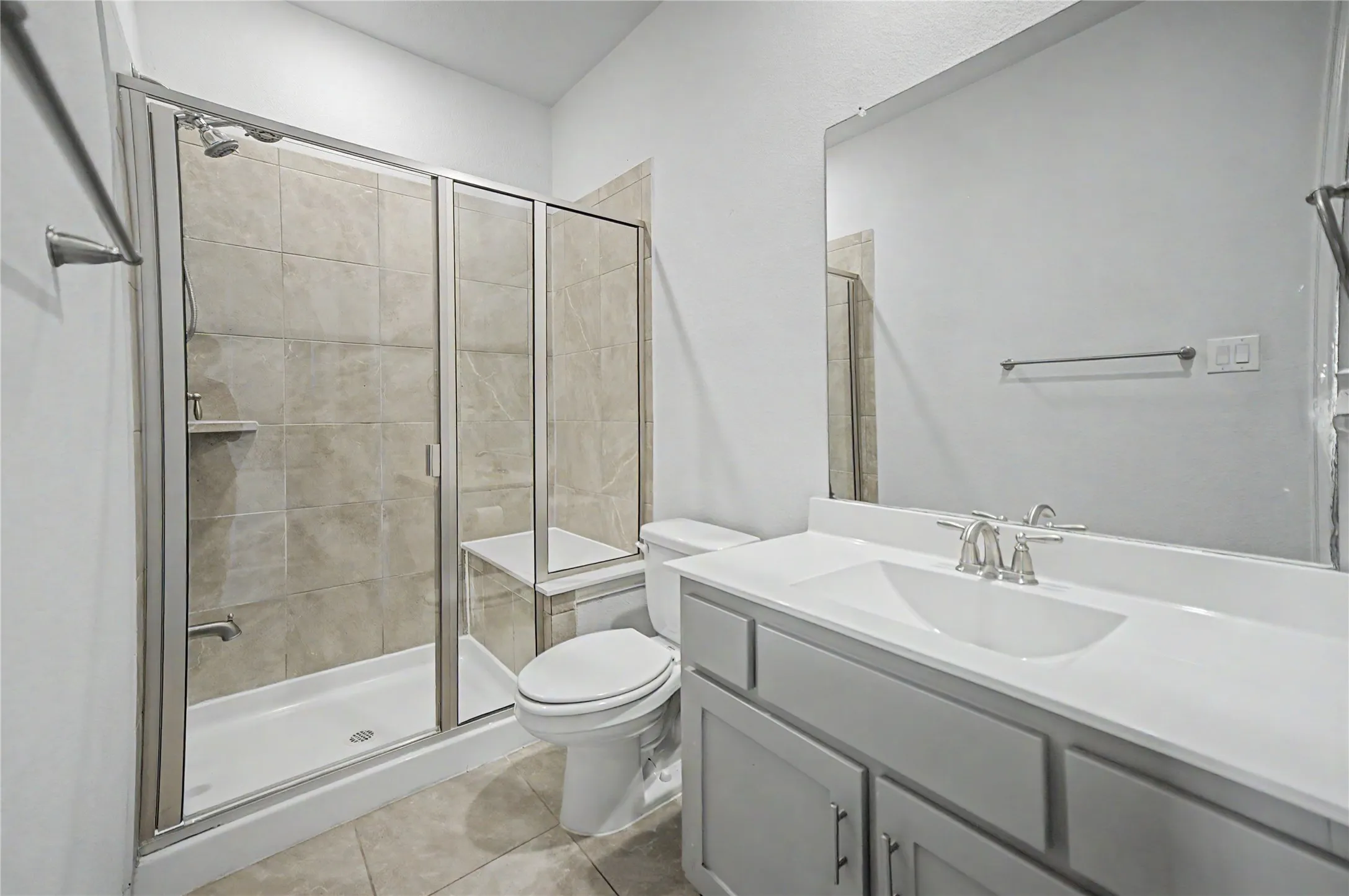 Shower enclosure with glass doors, built-in bench, and tiled walls