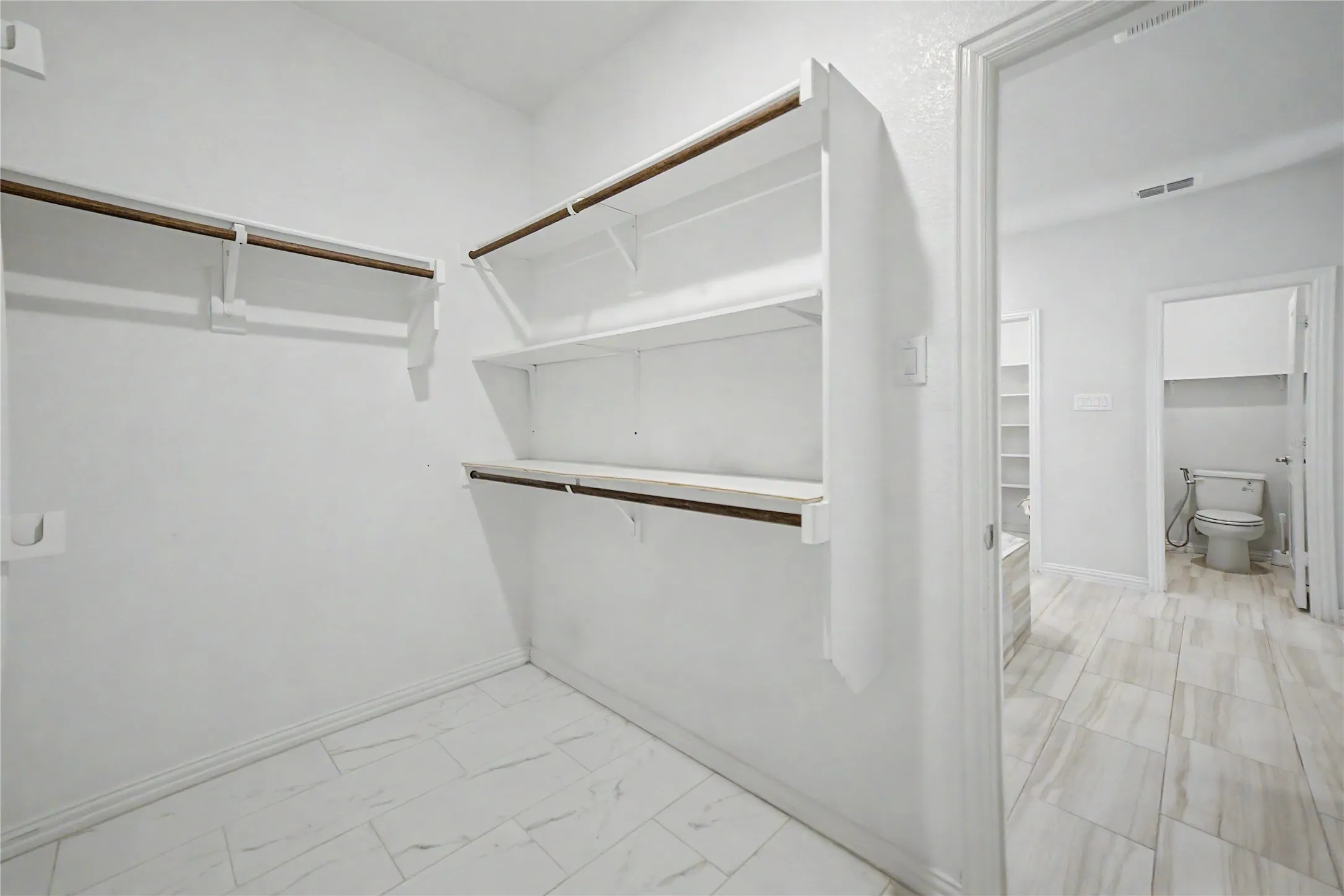 Walk-in closet featuring multiple shelving units and hanging rods