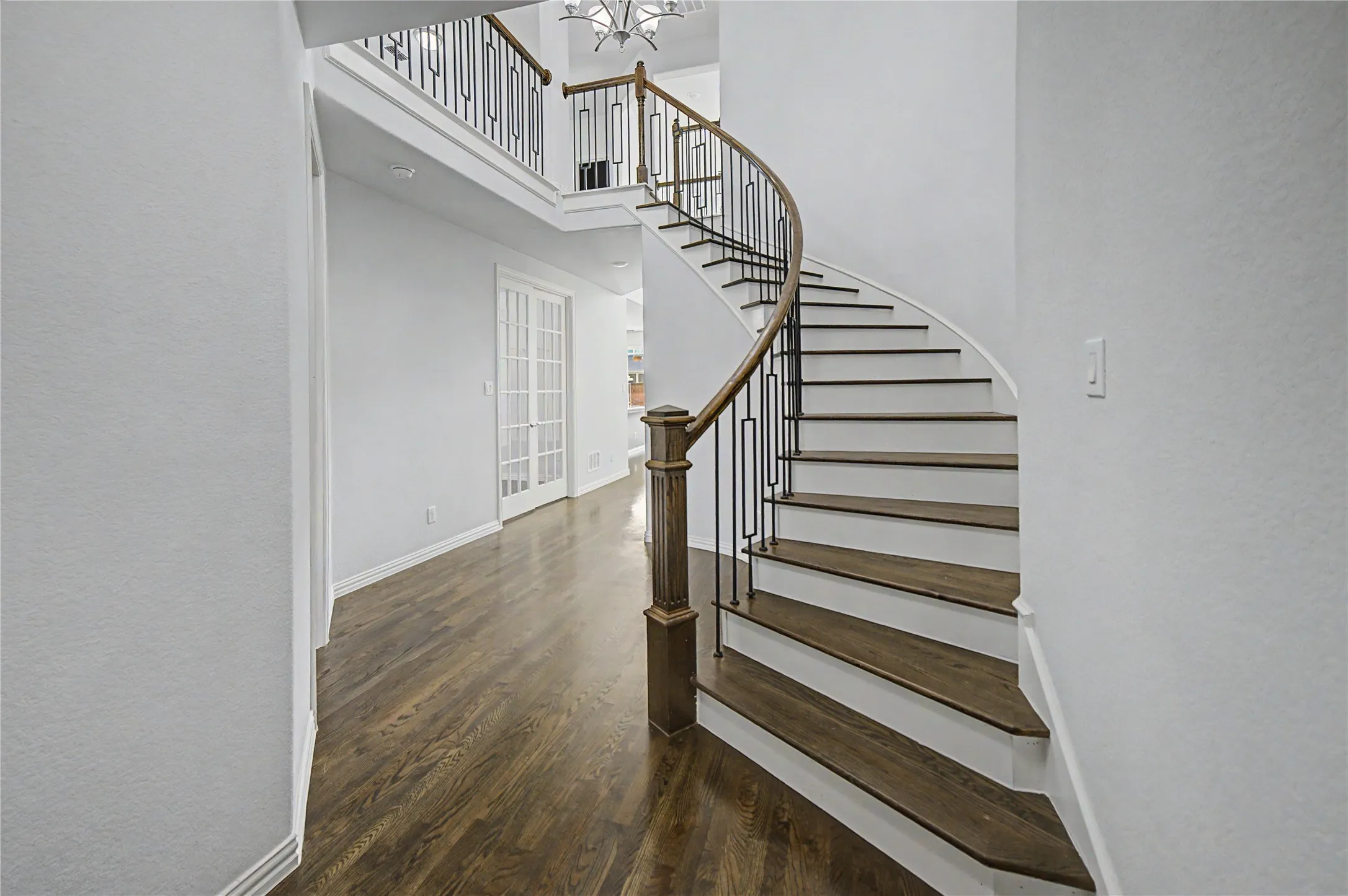 Curved staircase with wood-finish treads and wrought iron balusters