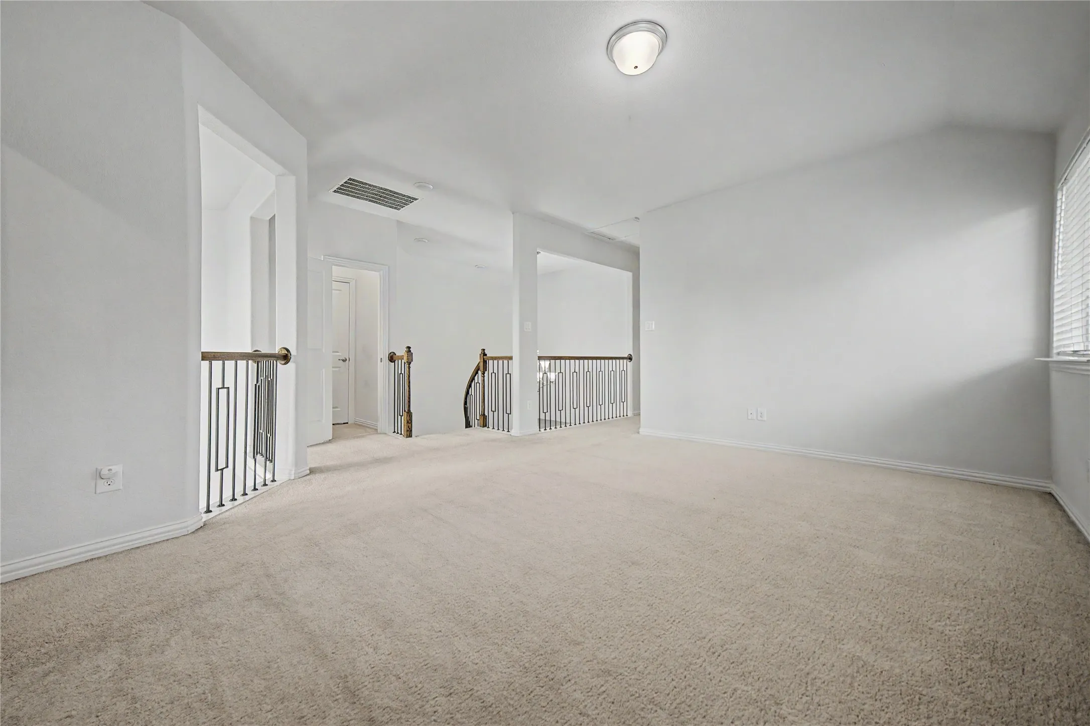 Spacious carpeted area with neutral wall tones, white trim, and a contemporary flush-mount ceiling light