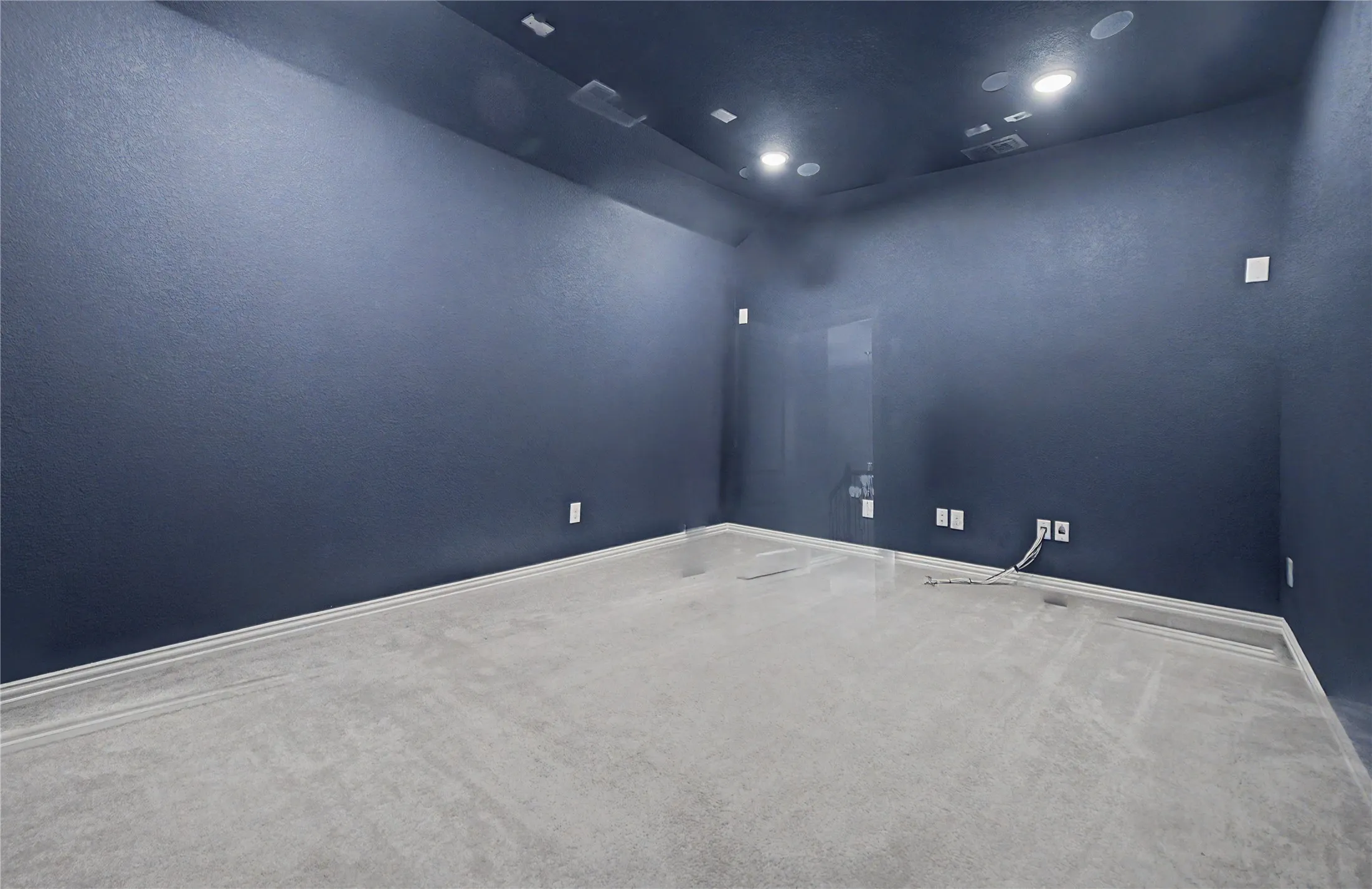 Textured dark blue walls, light gray carpeting, recessed ceiling lighting, and white trim